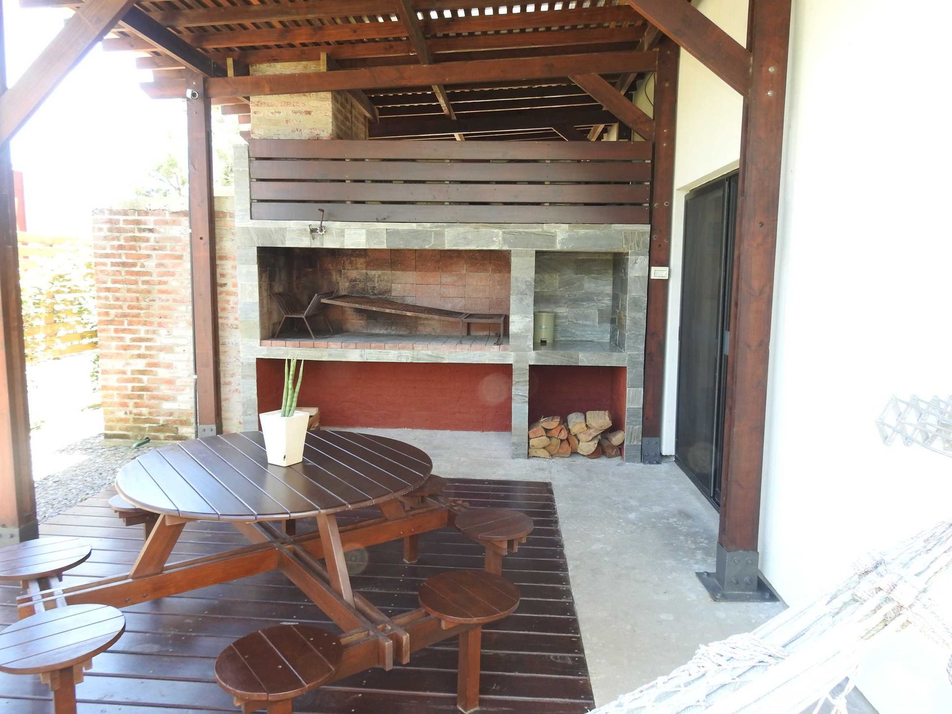 A wooden picnic table and chairs under a wooden roof
