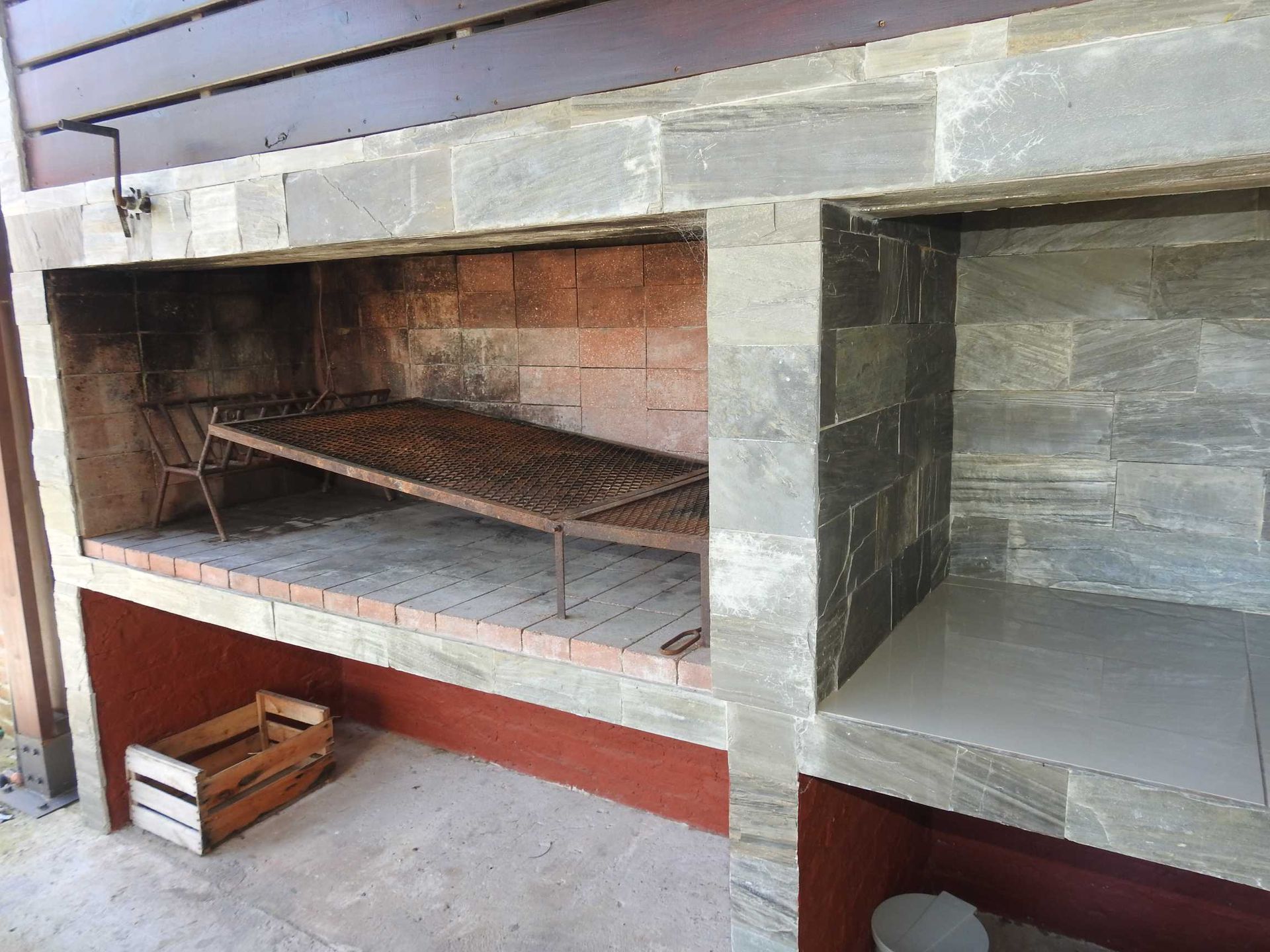 A wooden box is sitting next to a brick fireplace.