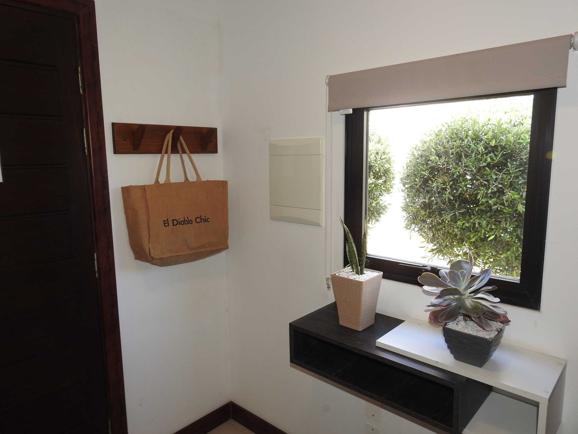 A brown bag hangs on a hook next to a window