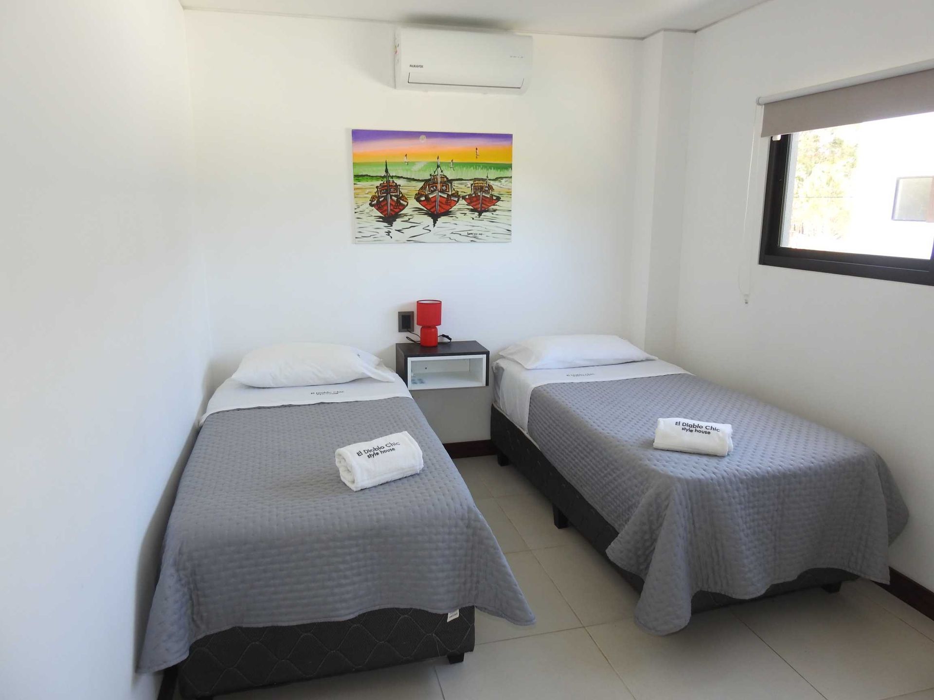 A bedroom with two beds and a painting on the wall