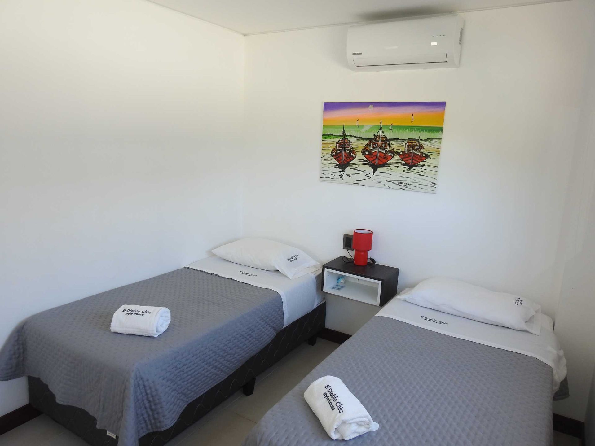 A bedroom with two beds and a painting on the wall