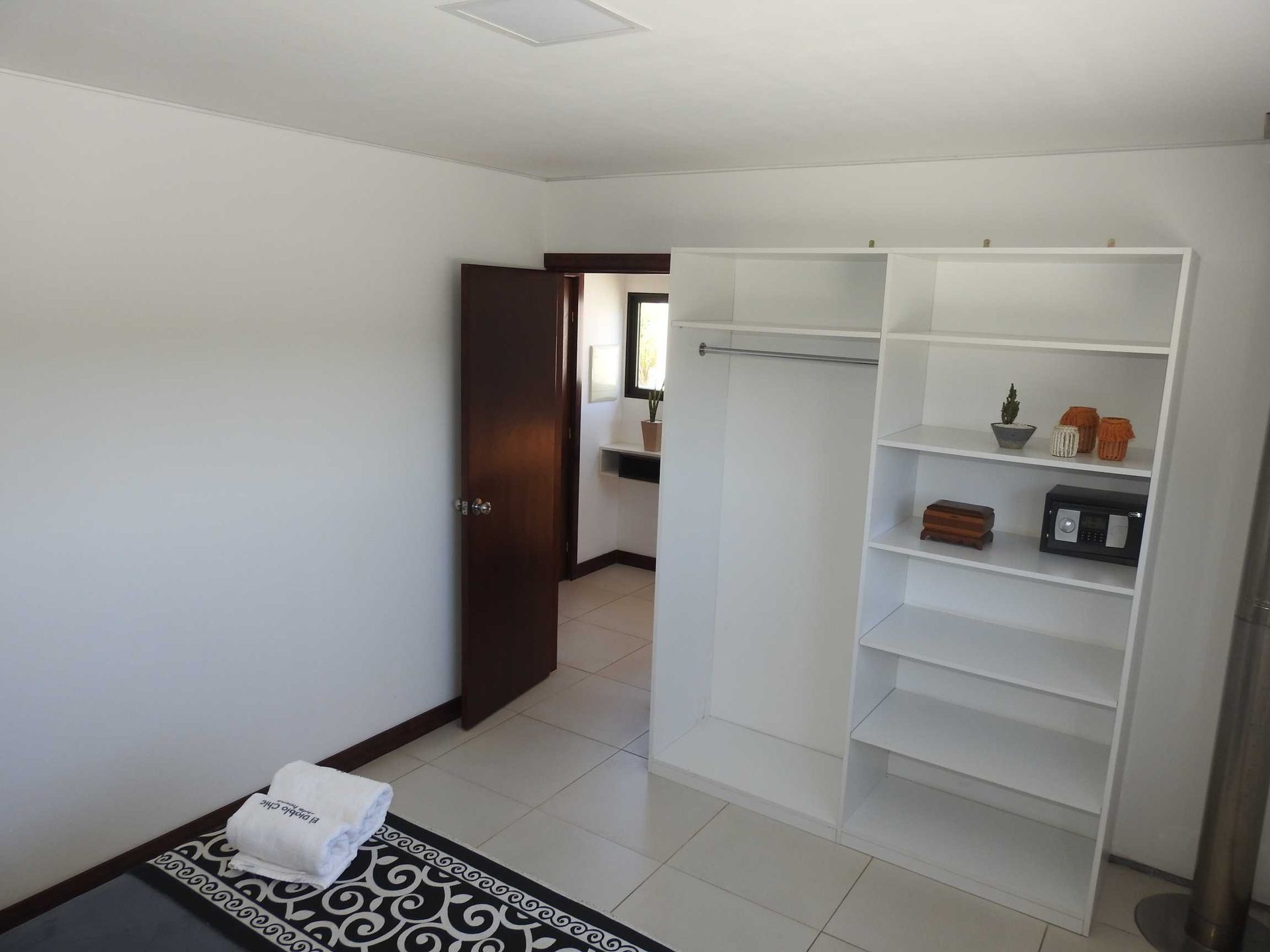 A bedroom with a wardrobe and a rug on the floor