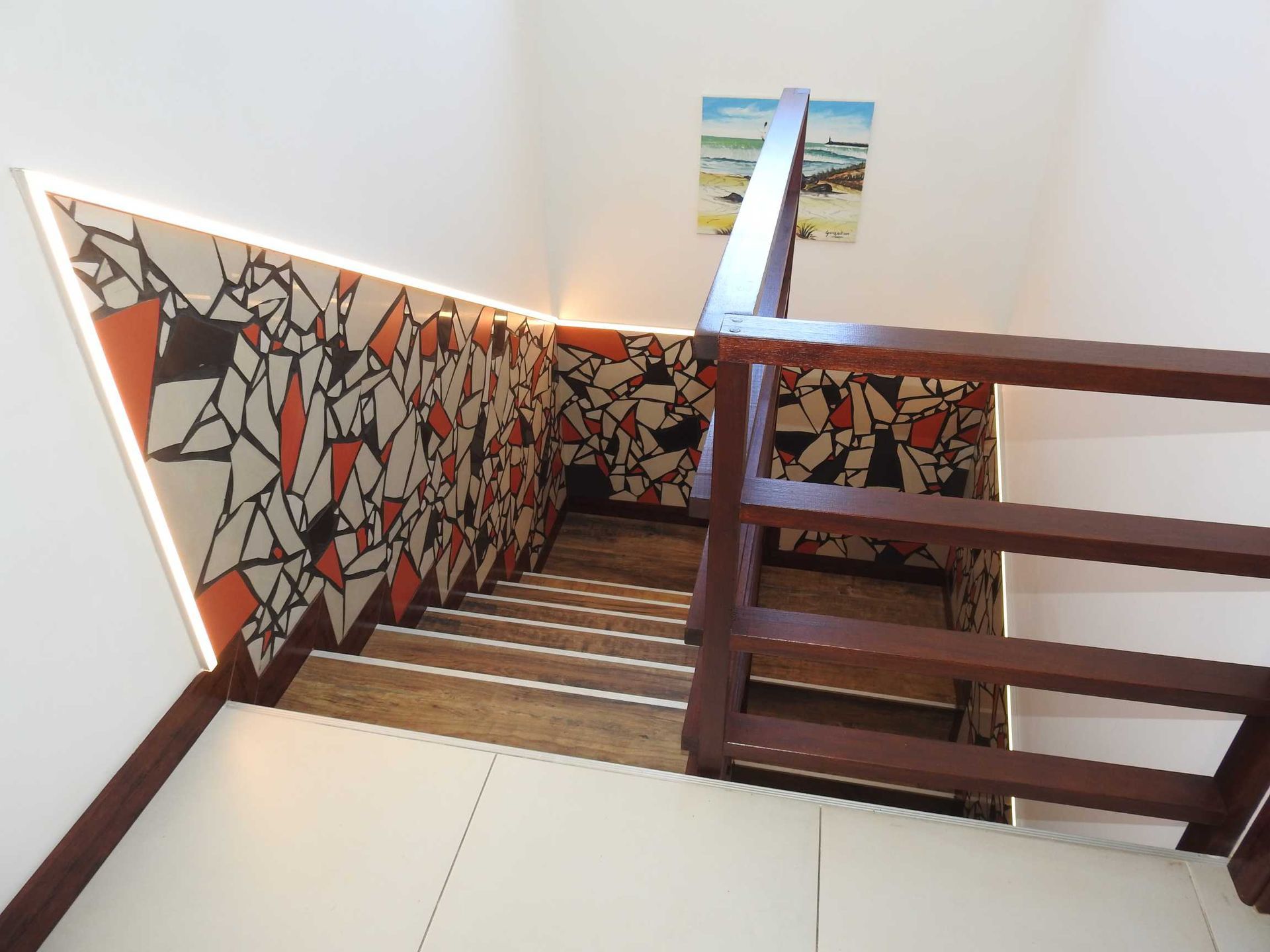 A staircase with a wooden railing and a painting on the wall