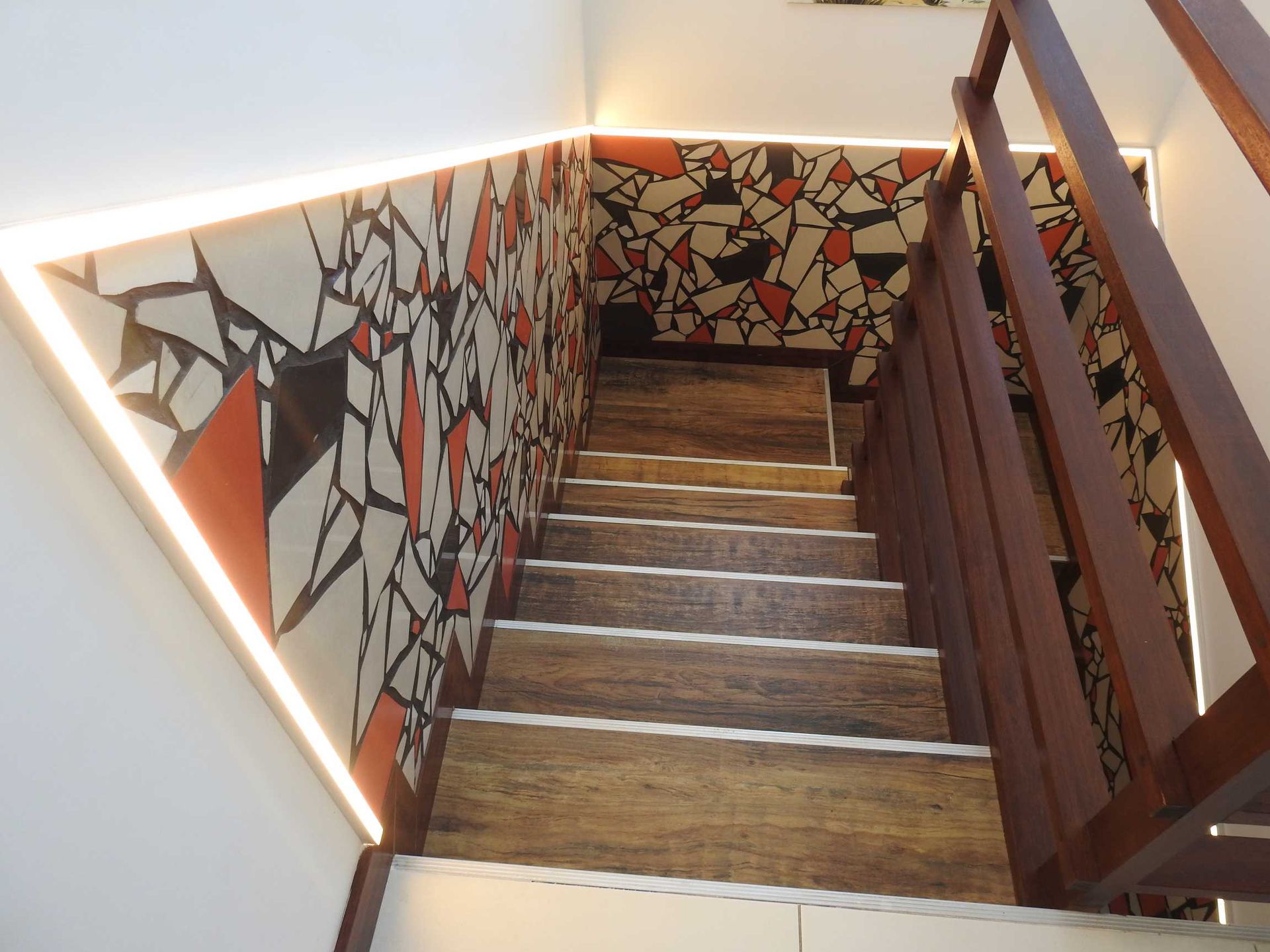 A wooden staircase with a geometric pattern on the wall