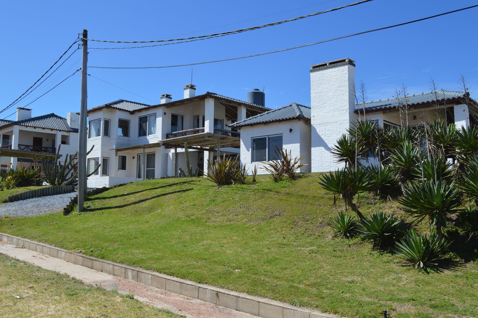 A large white house is sitting on top of a grassy hill.