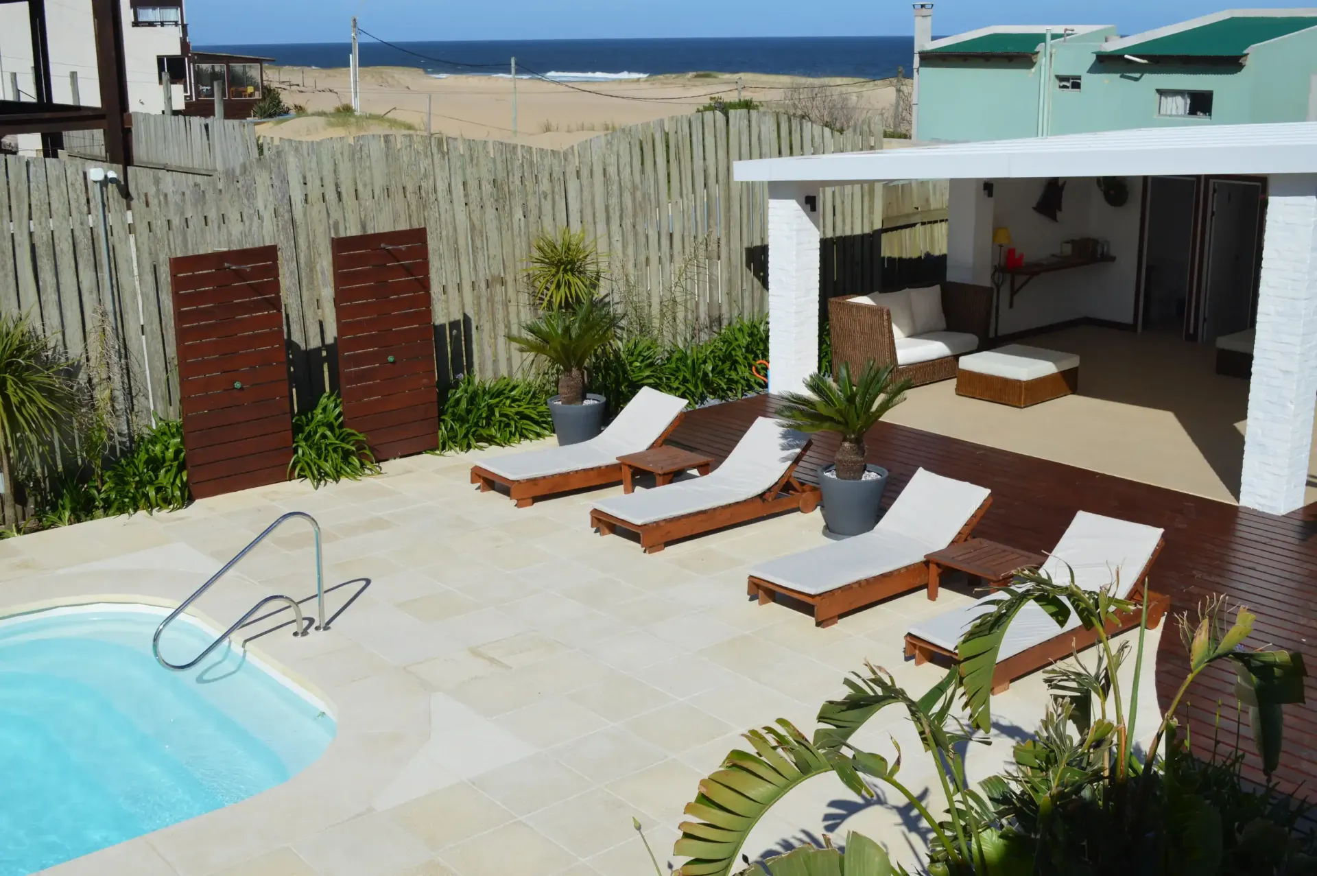 A swimming pool surrounded by lounge chairs with a view of the ocean