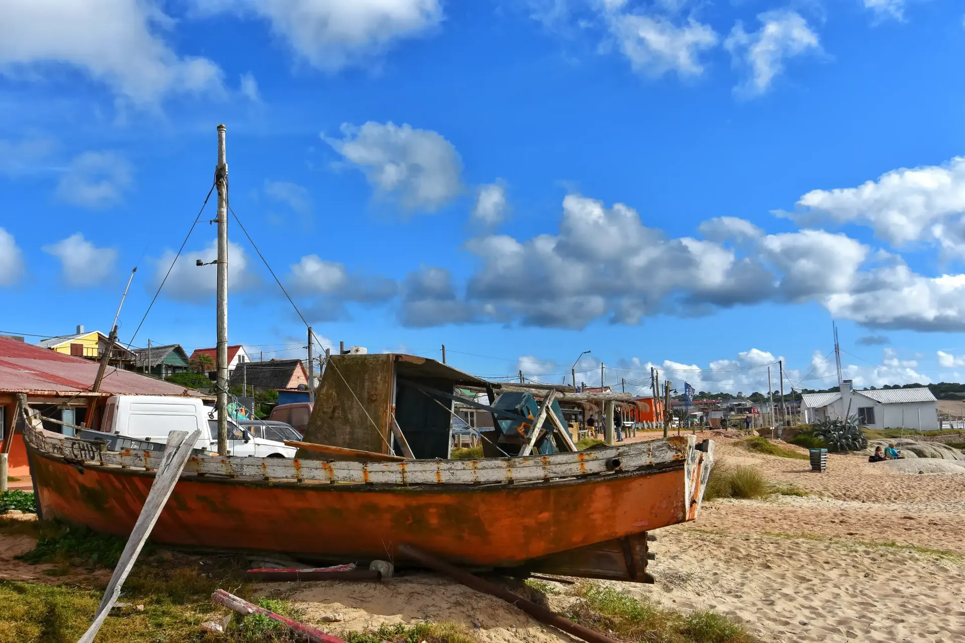 An old rusty boat is sitting on a sandy beach.