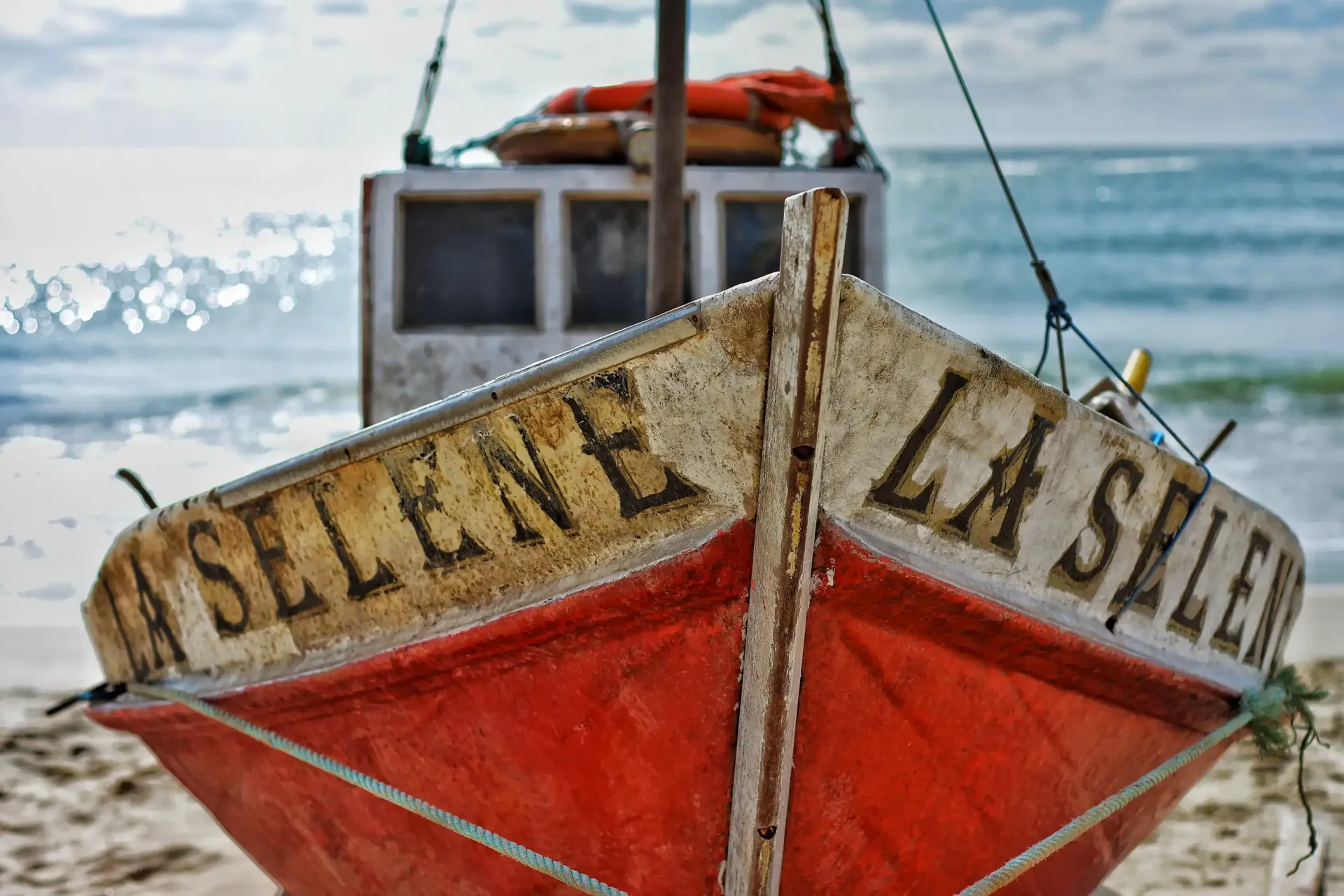 A red boat called la selene is sitting on the beach