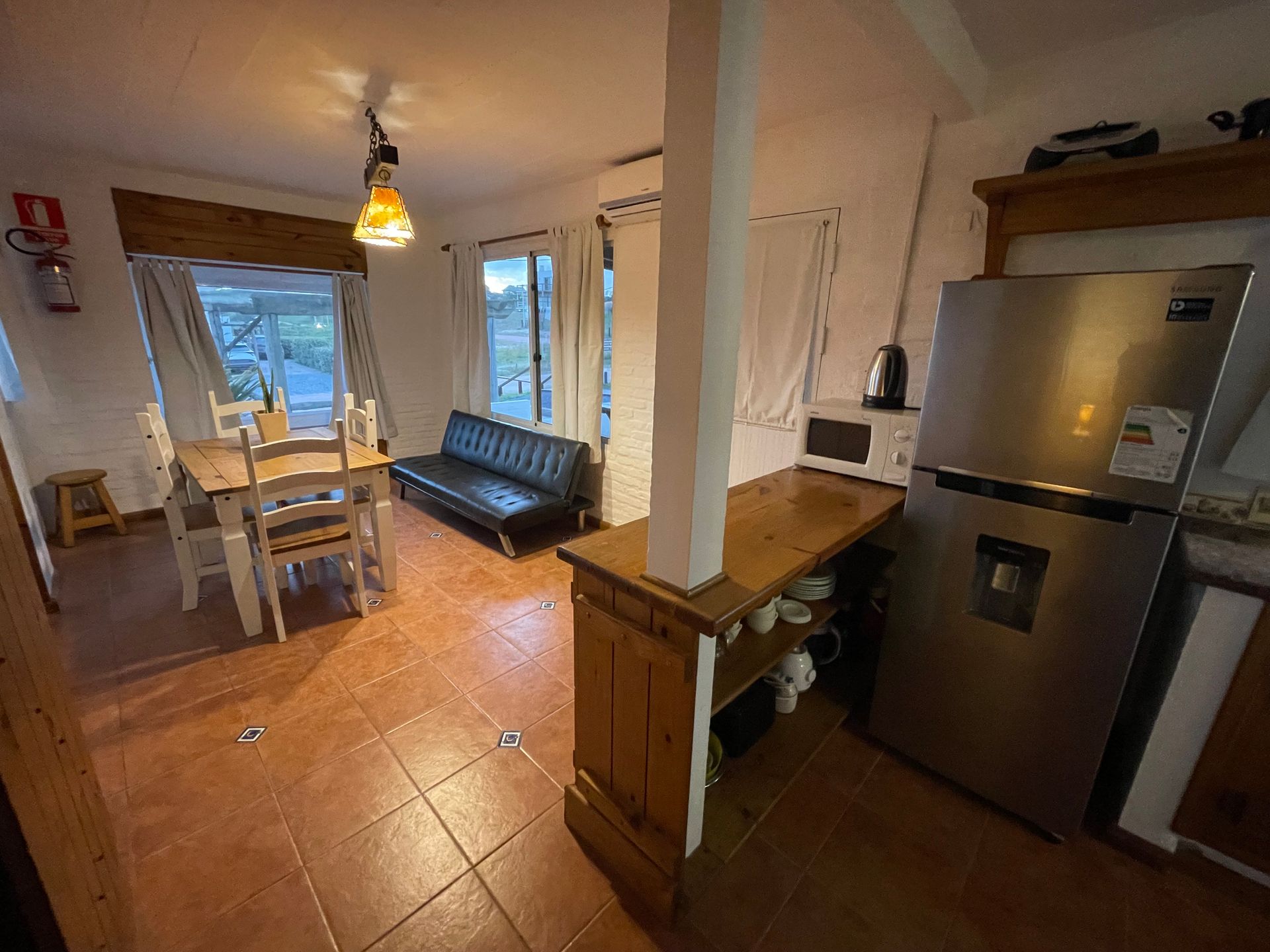 A kitchen with a refrigerator , table , chairs and a couch.