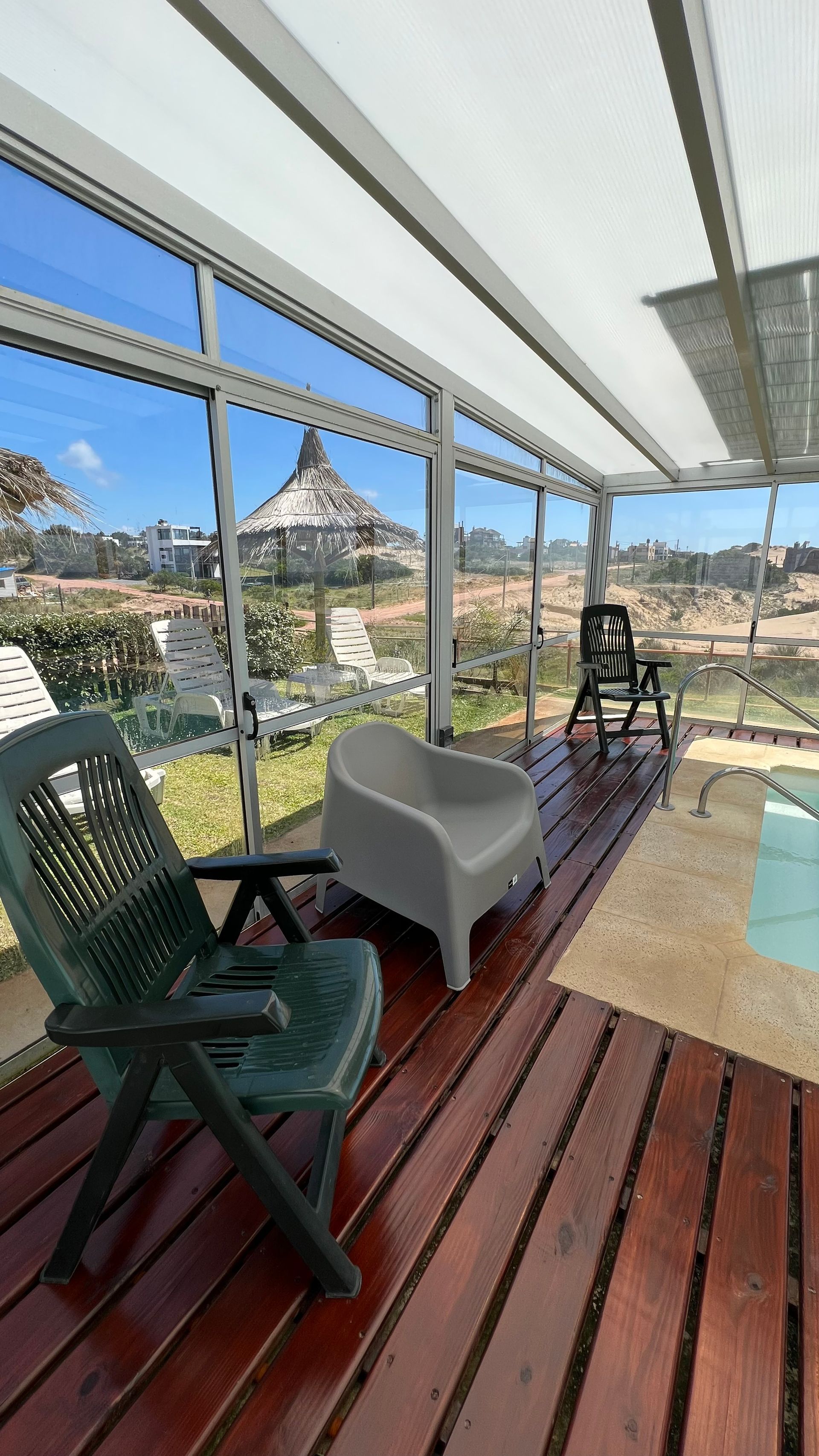 A wooden deck with chairs and a swimming pool in the background.