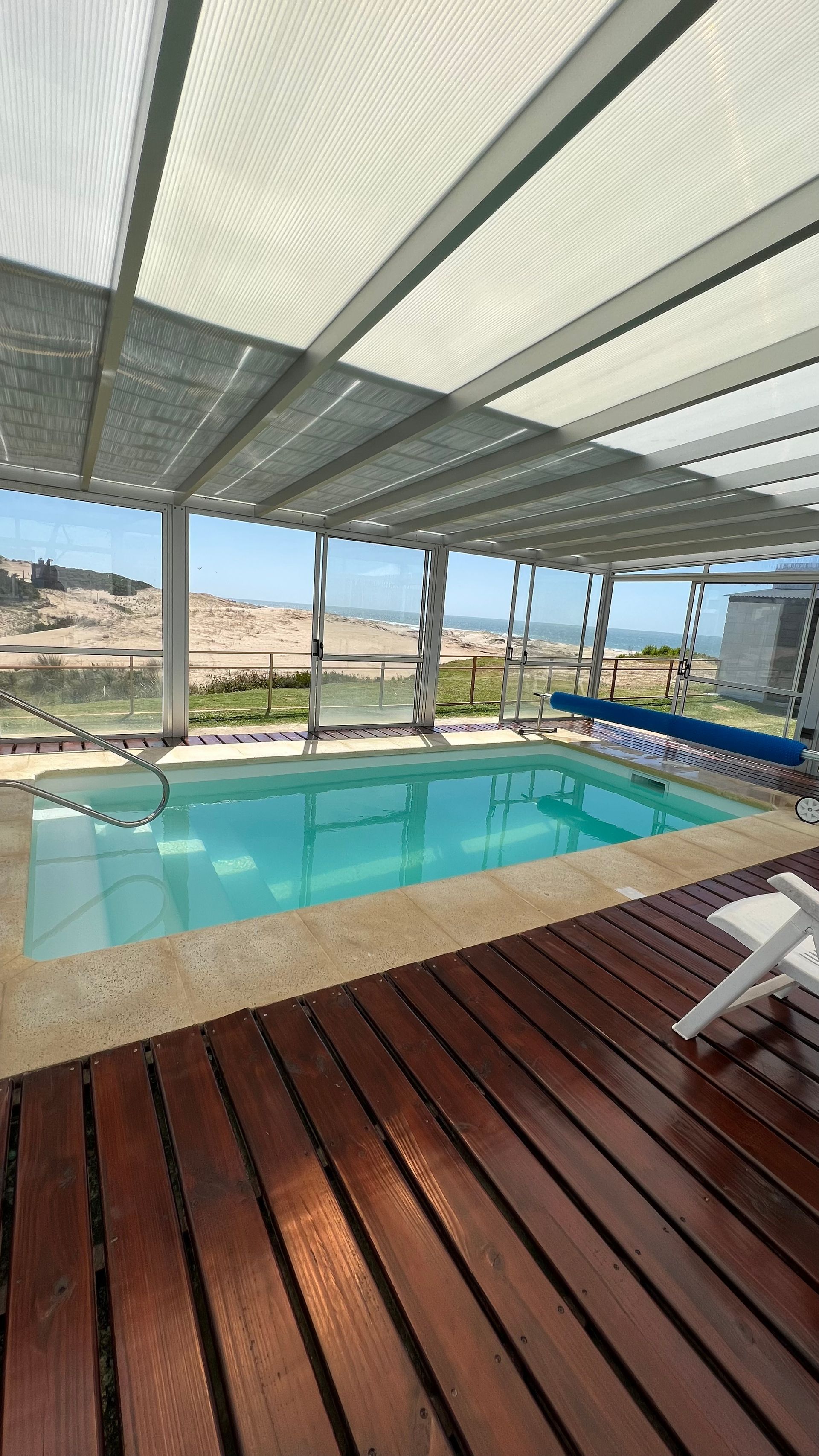 A large indoor swimming pool with a wooden deck surrounding it.