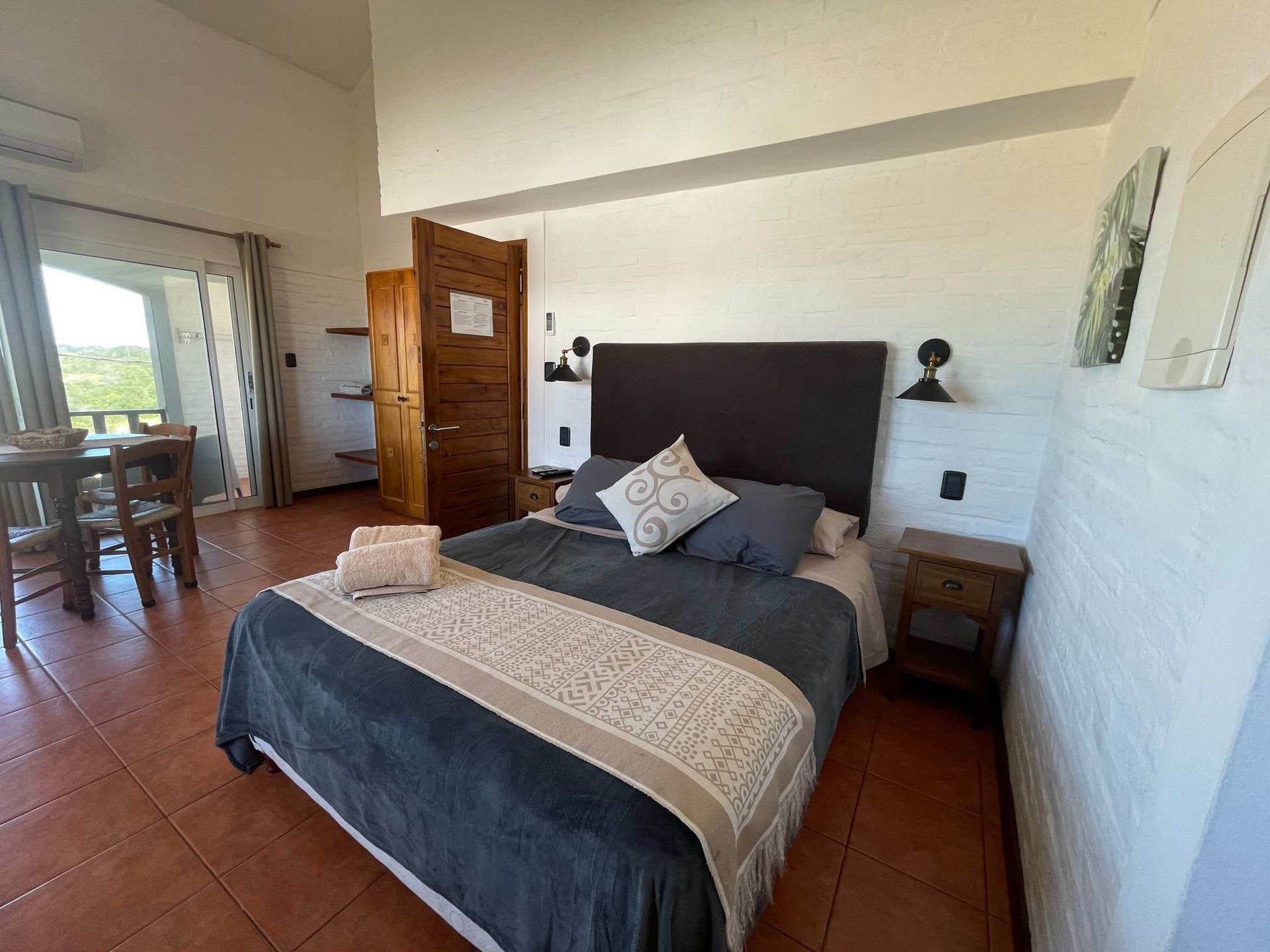 A bedroom with a bed , nightstand , table and chairs.