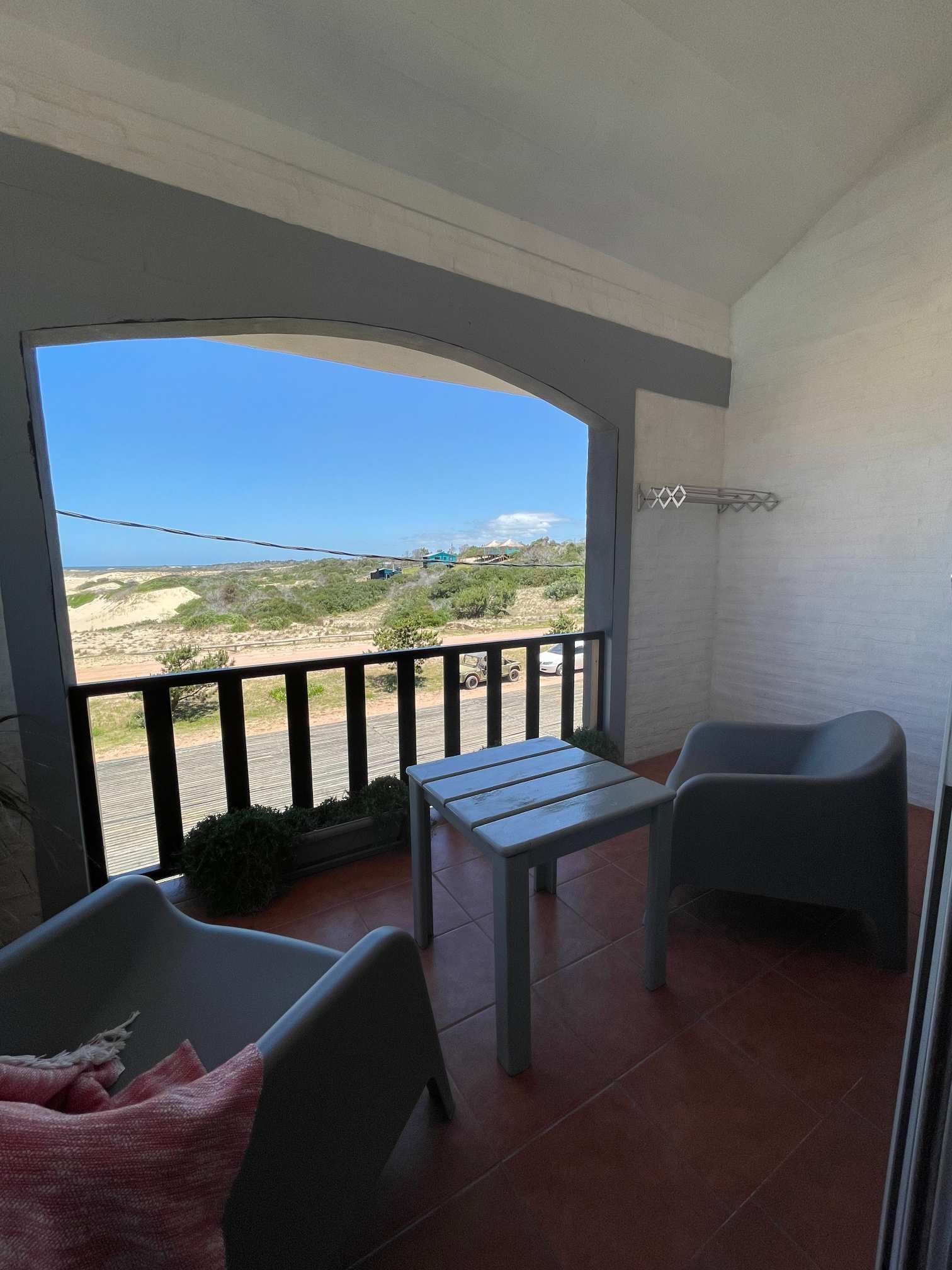 A balcony with two chairs and a table with a view of the ocean.