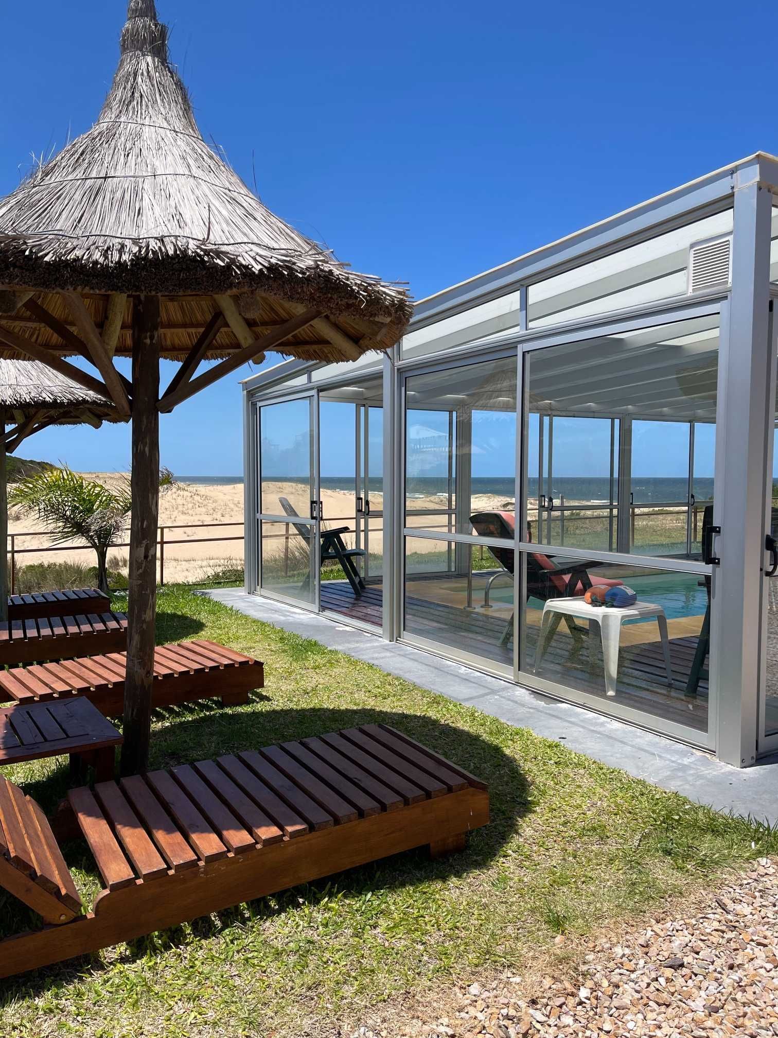 A straw umbrella is sitting in front of a swimming pool.
