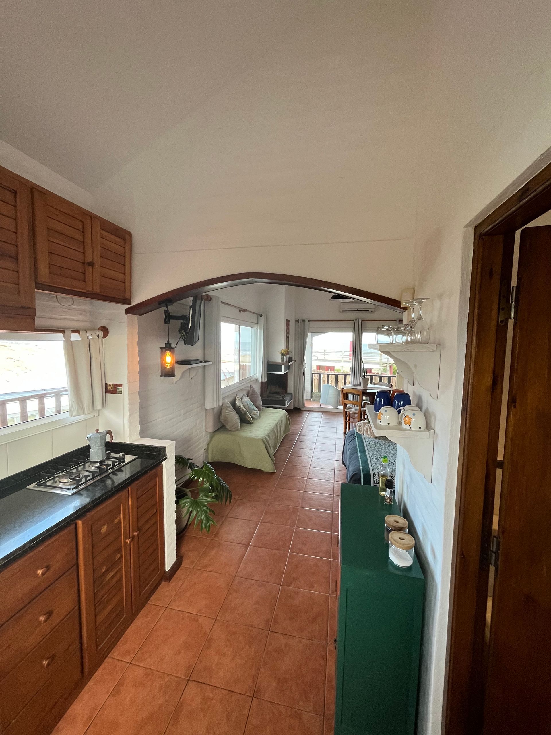 A kitchen with a stove , sink , cabinets and a couch.