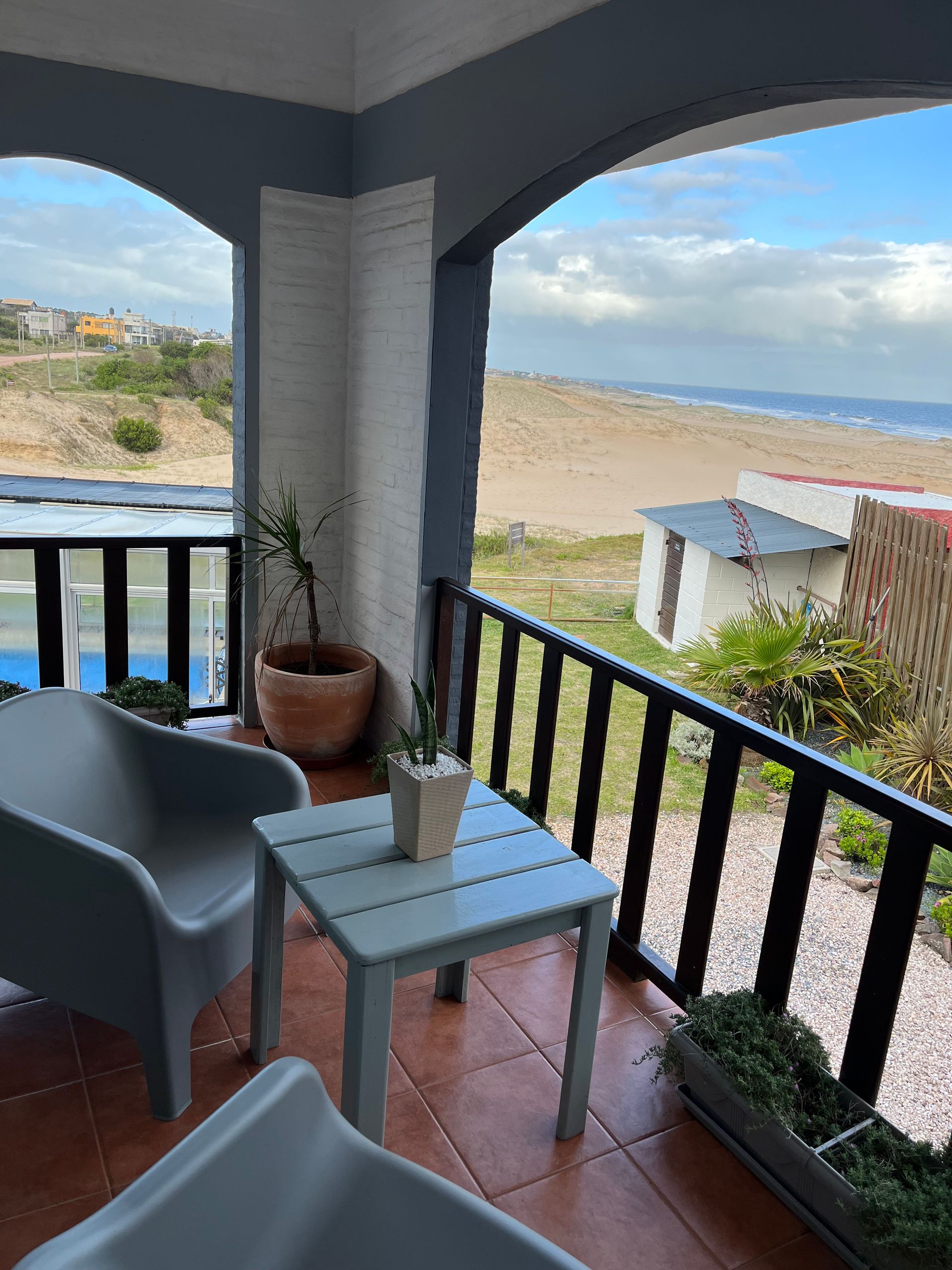 A balcony with chairs and a table with a view of the beach.