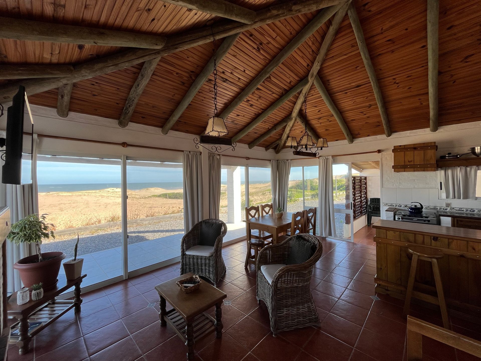 A living room with a wooden ceiling and a view of the ocean