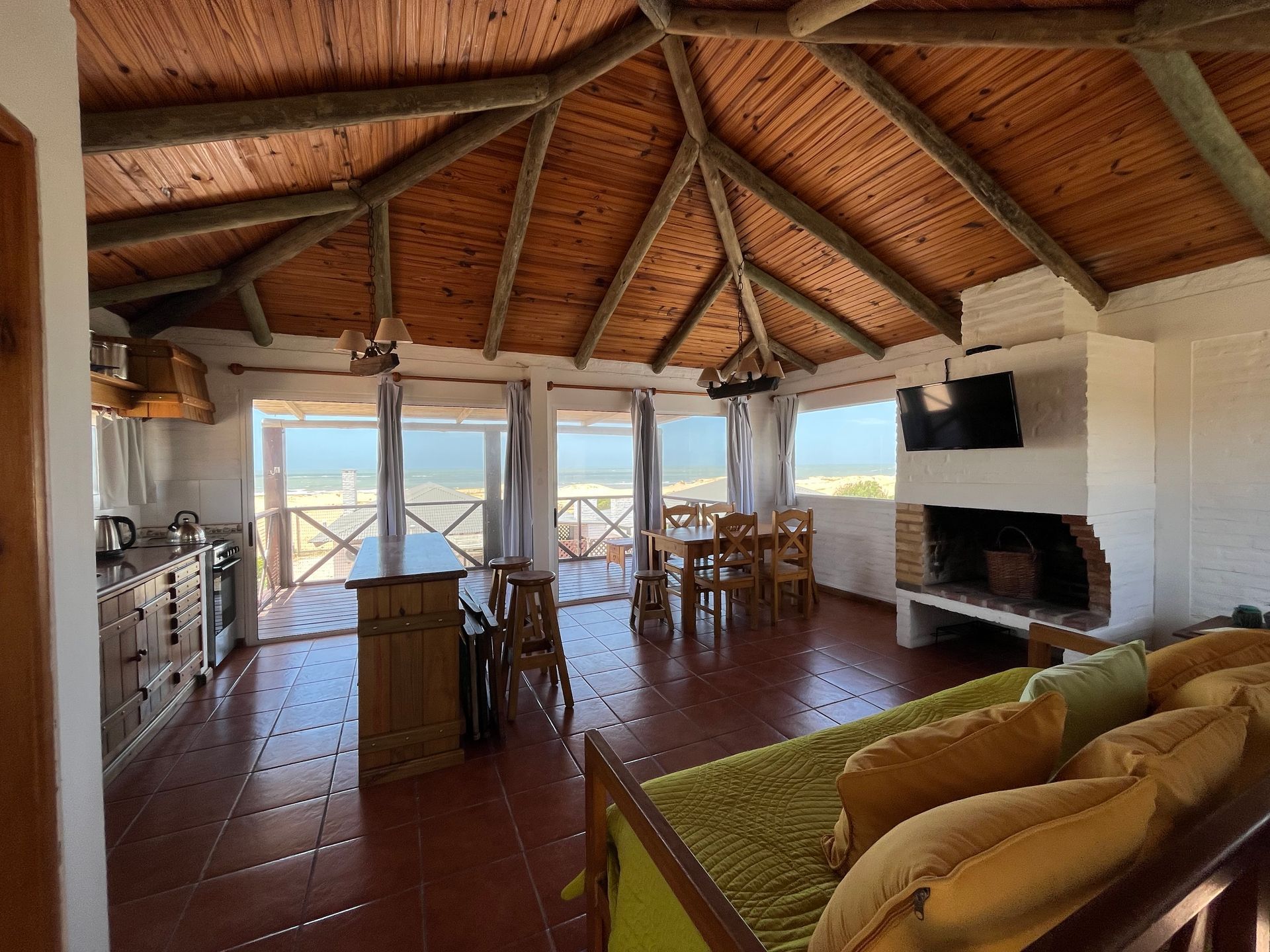 A living room with a wooden ceiling and a fireplace