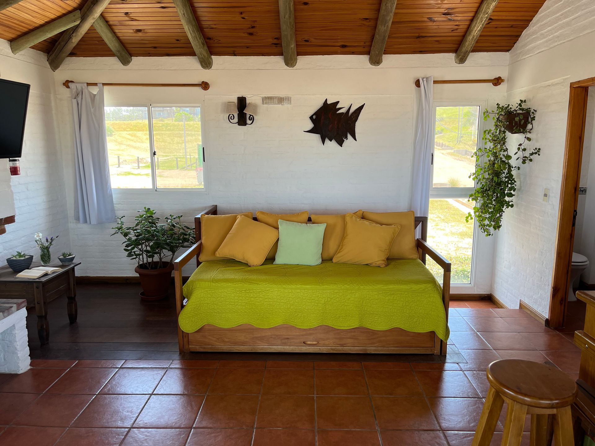 A living room with a green couch and yellow pillows