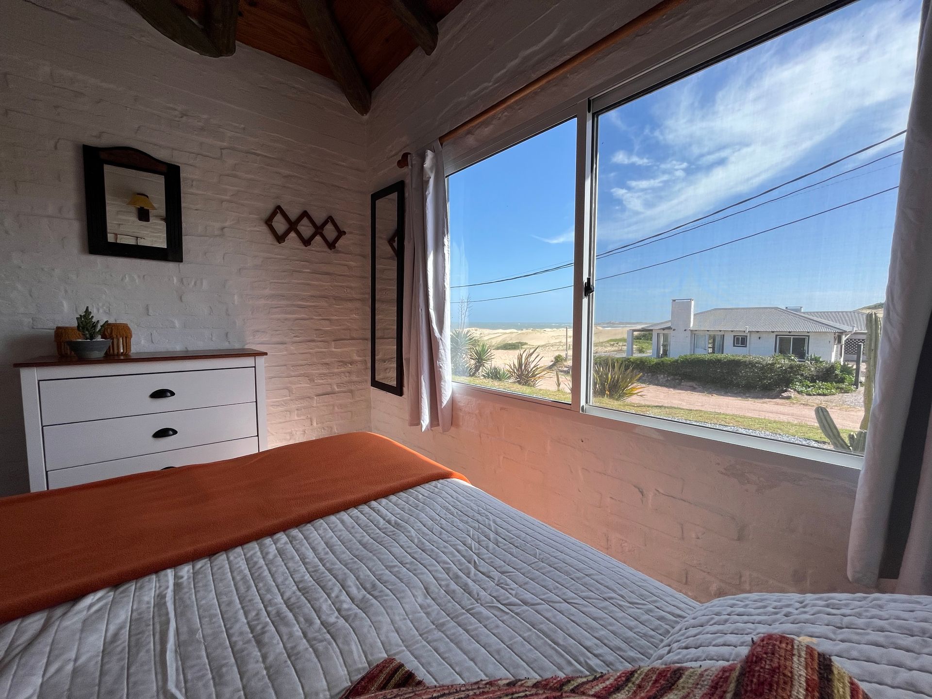 A bedroom with a bed and a large window with a view of the ocean.