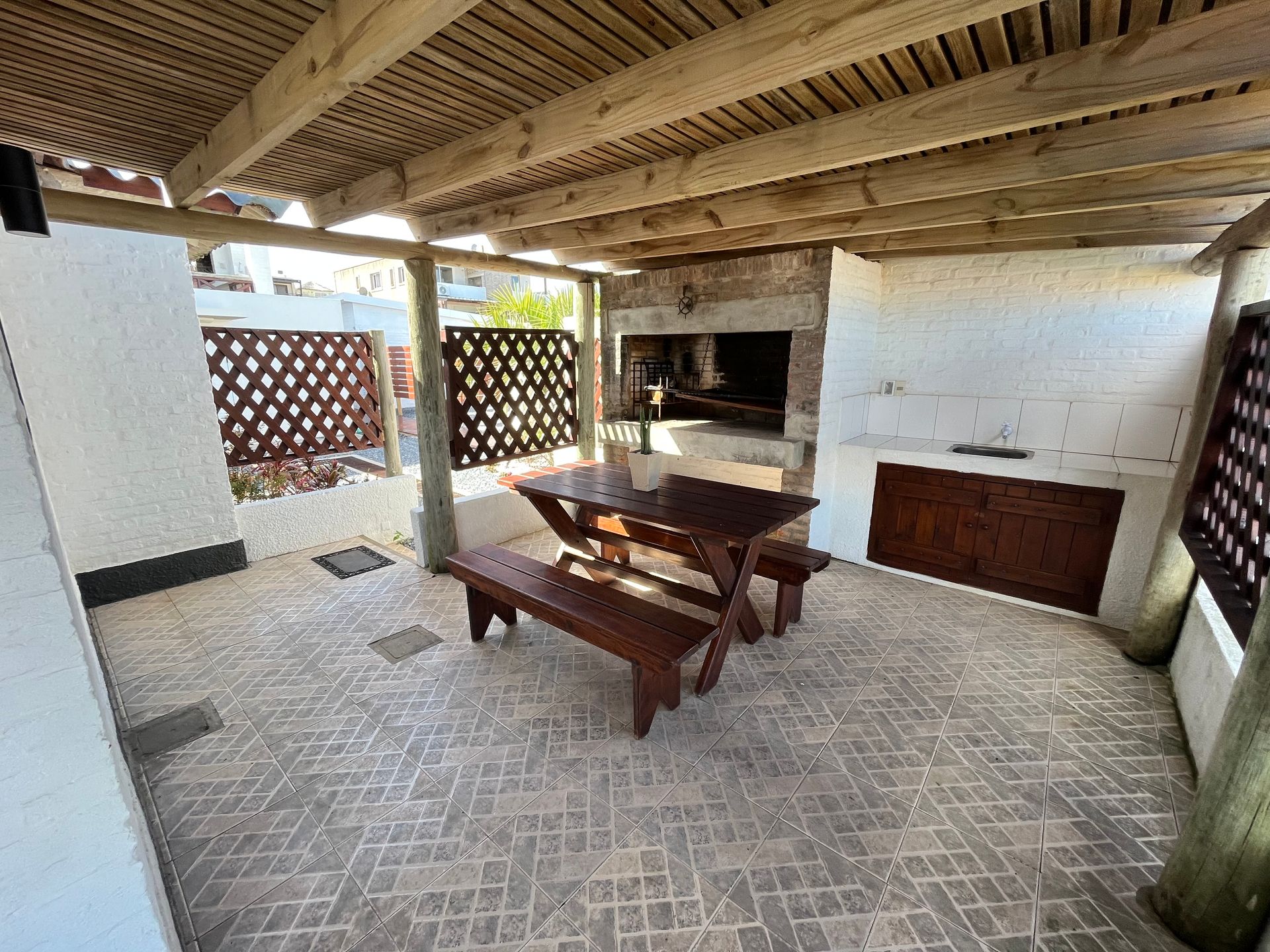 A wooden picnic table and benches under a wooden roof.