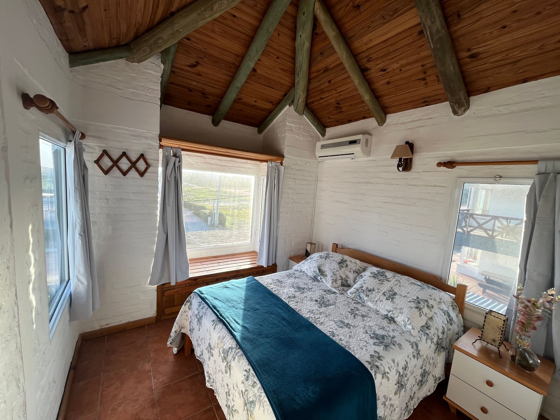 A bedroom with a bed and a window with a wooden ceiling.