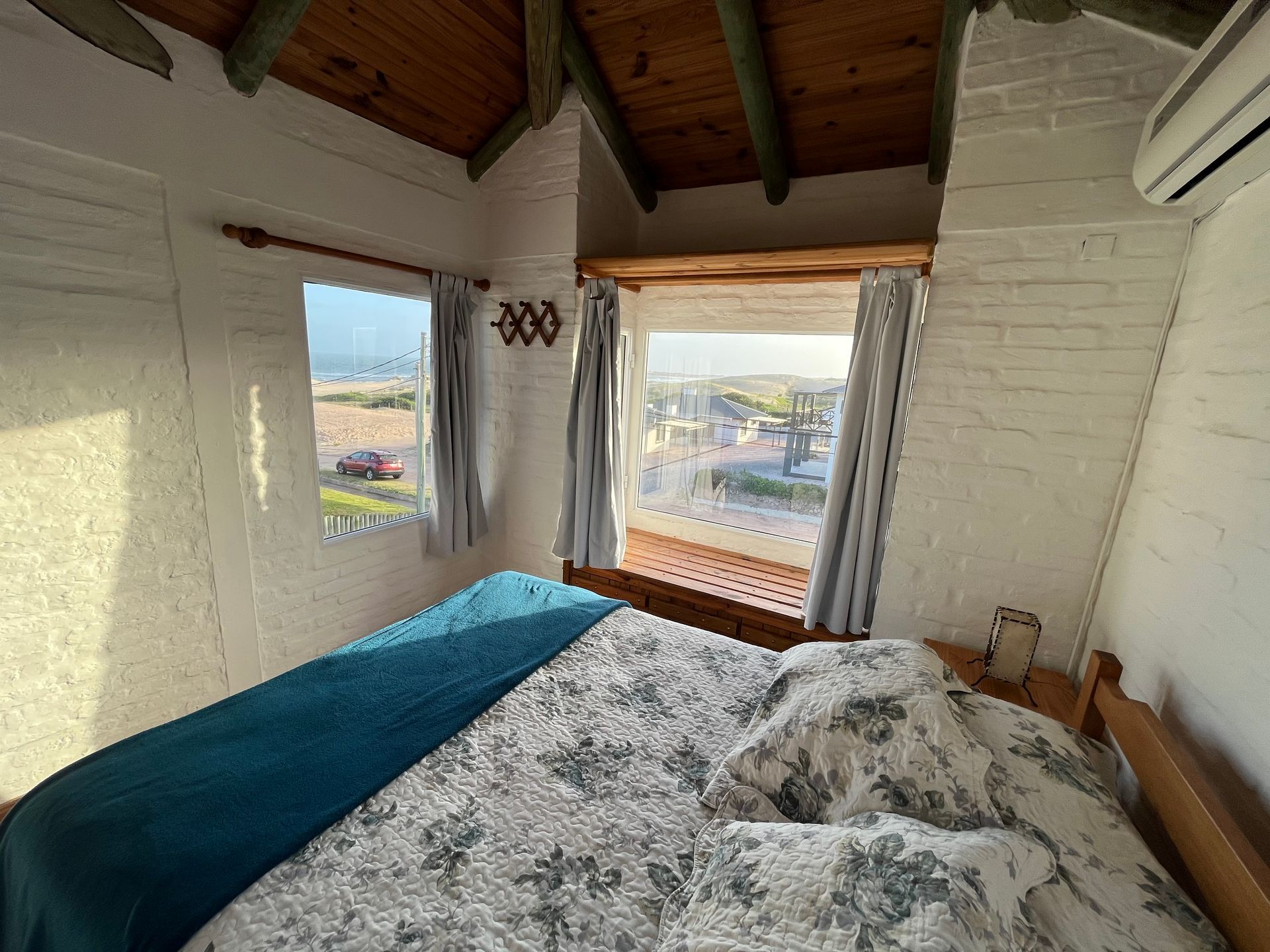 A bedroom with a bed and a window with a view of the ocean.