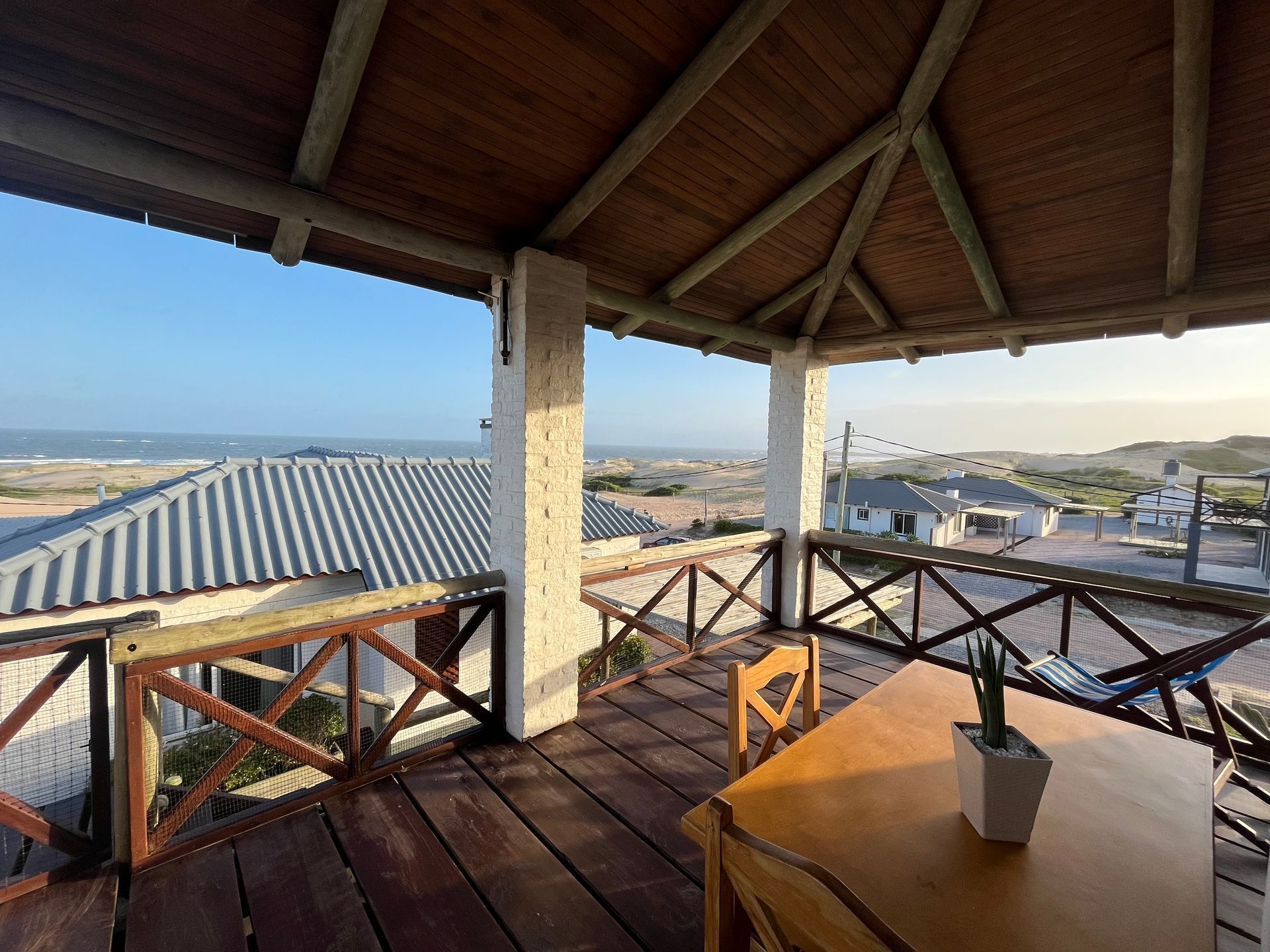 A wooden deck with a table and chairs overlooking the ocean