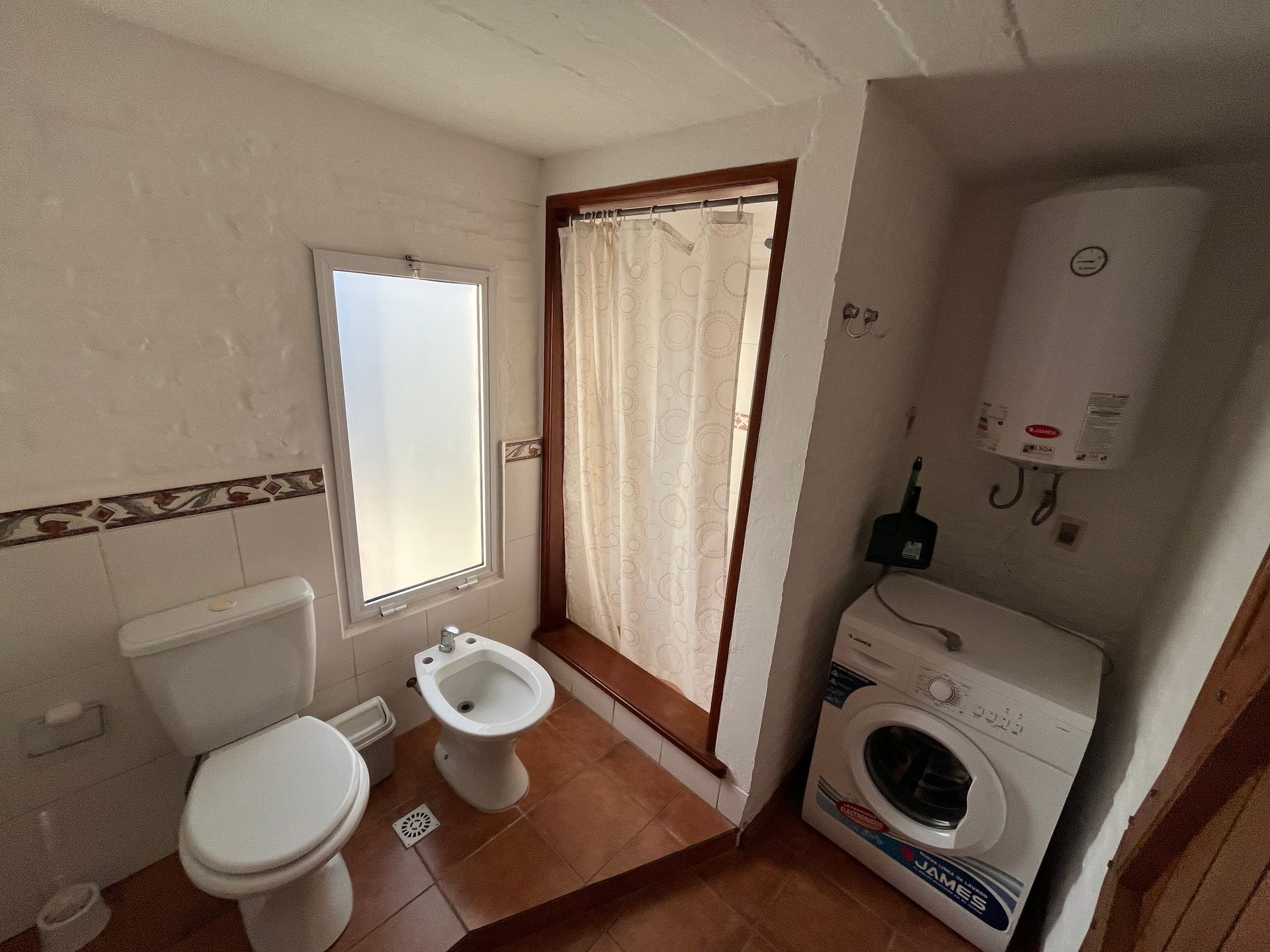 A bathroom with a toilet , bidet and washing machine