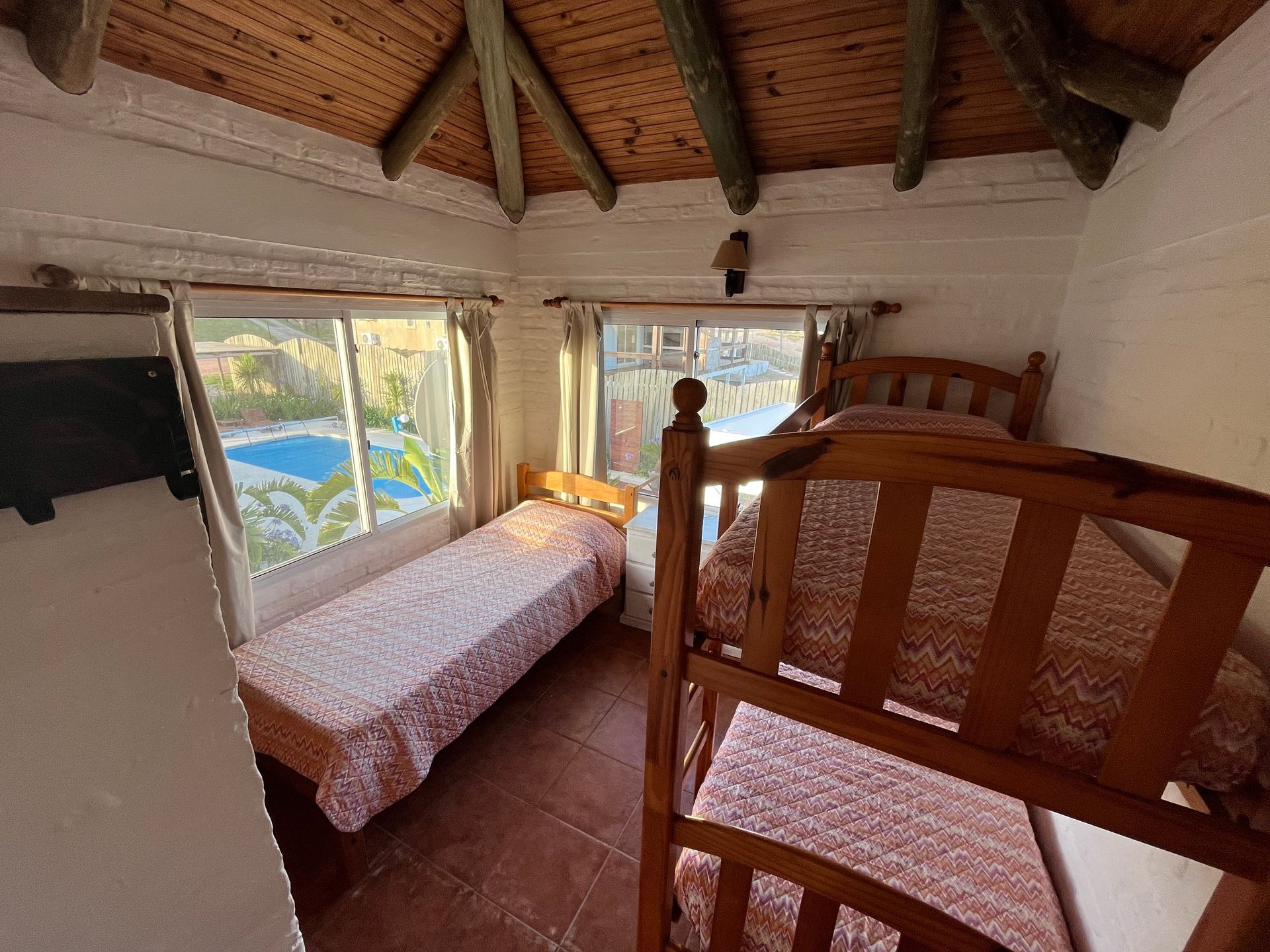 A bedroom with two beds and a swimming pool in the background