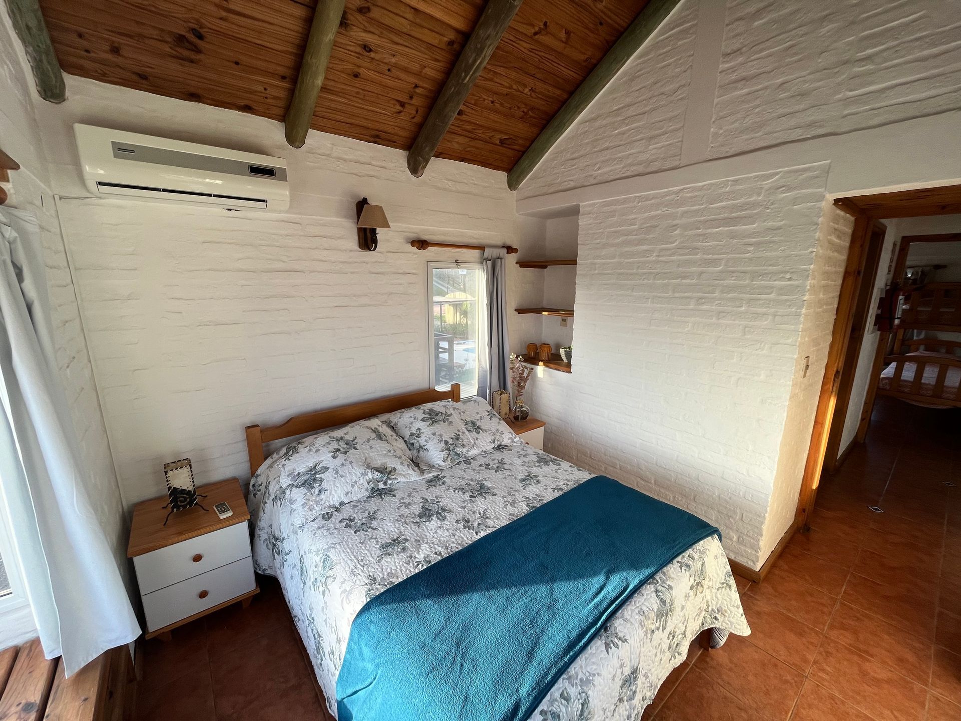 A bedroom with a bed , nightstand , and air conditioner.