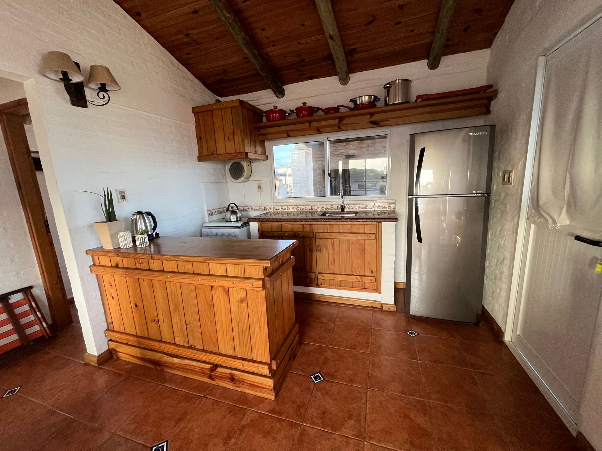 A kitchen with a refrigerator , sink , and wooden cabinets.