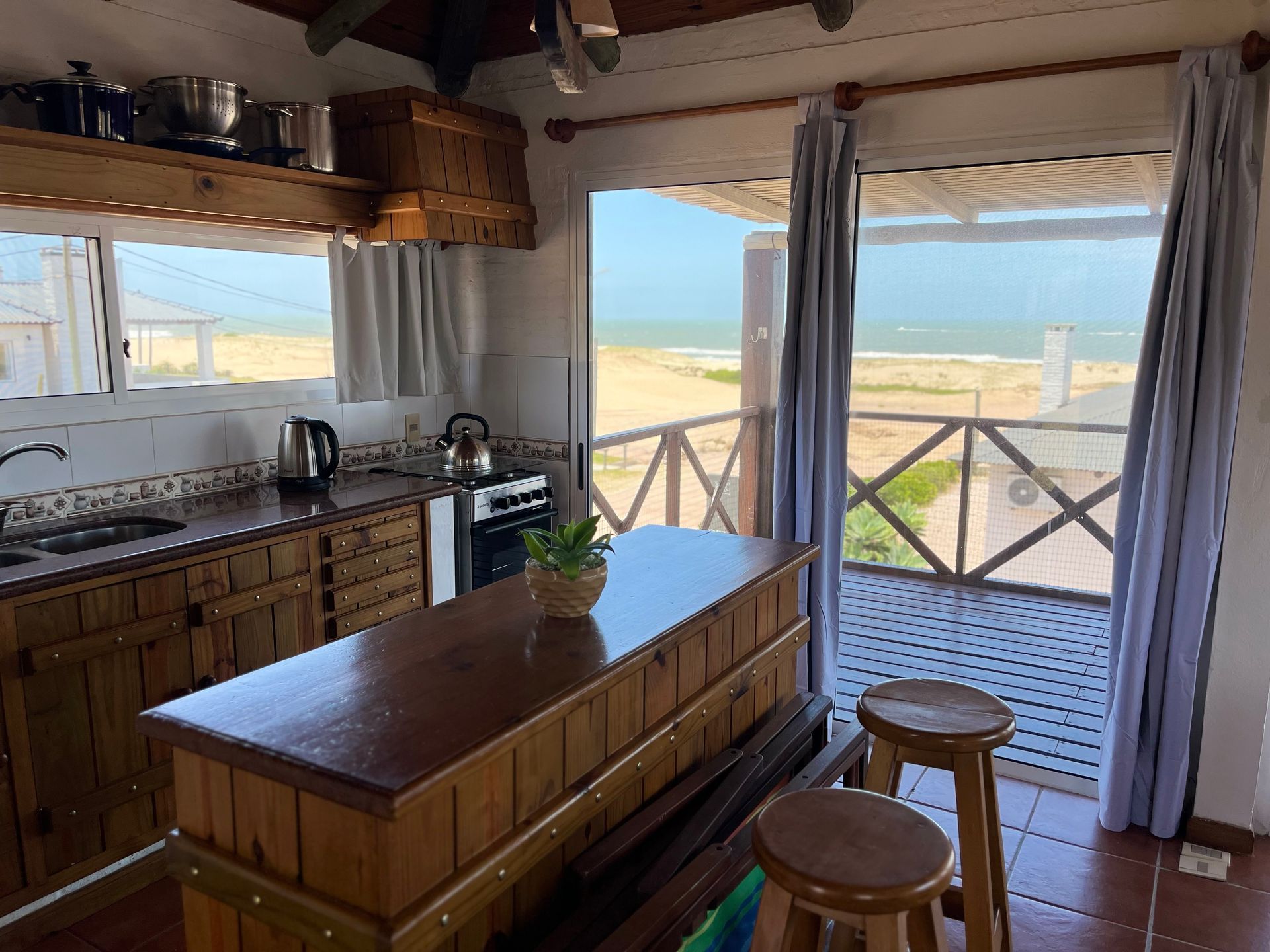 A kitchen with a large island and stools and a view of the ocean.