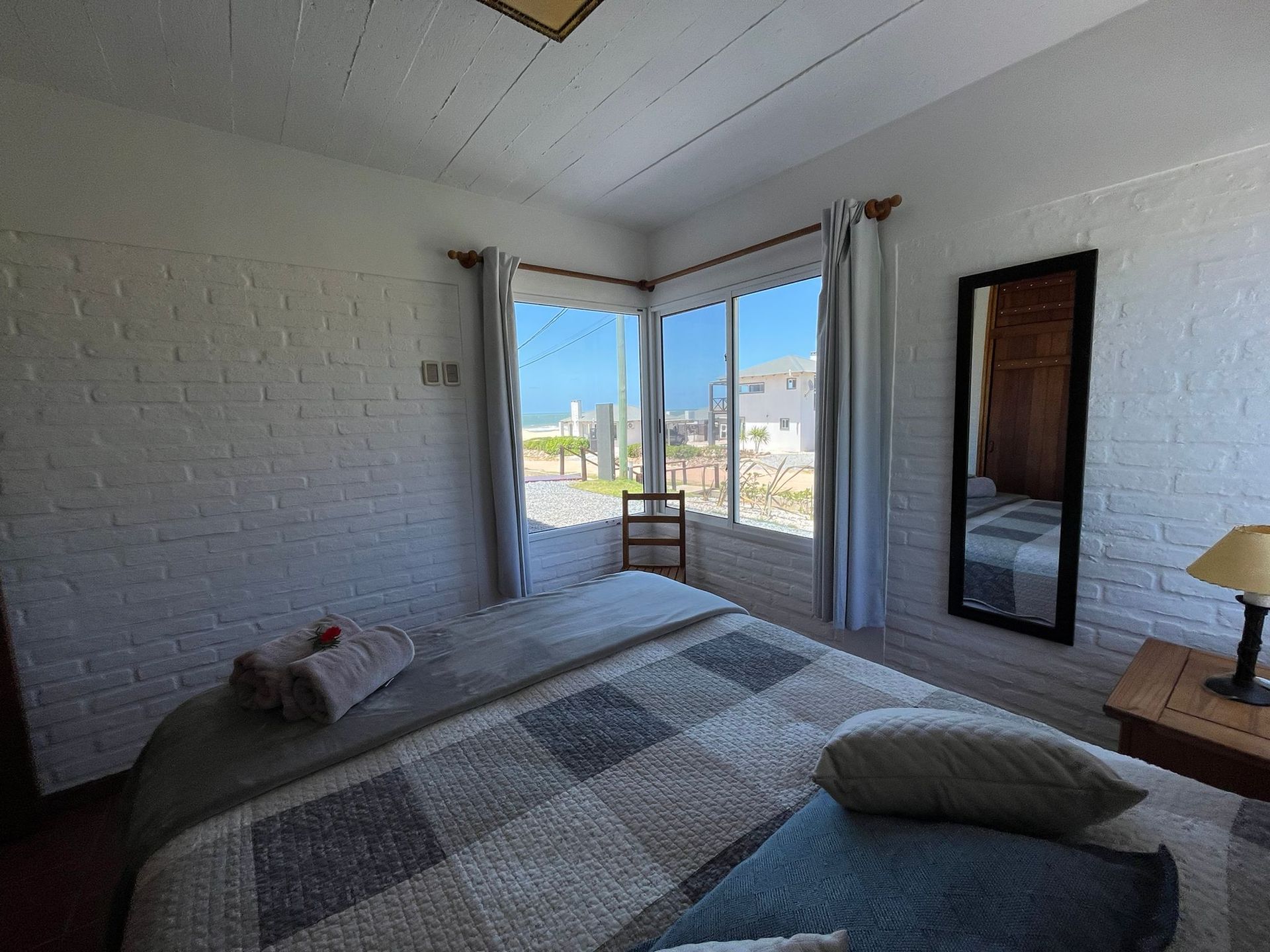 A bedroom with a large bed , a mirror and a large window.