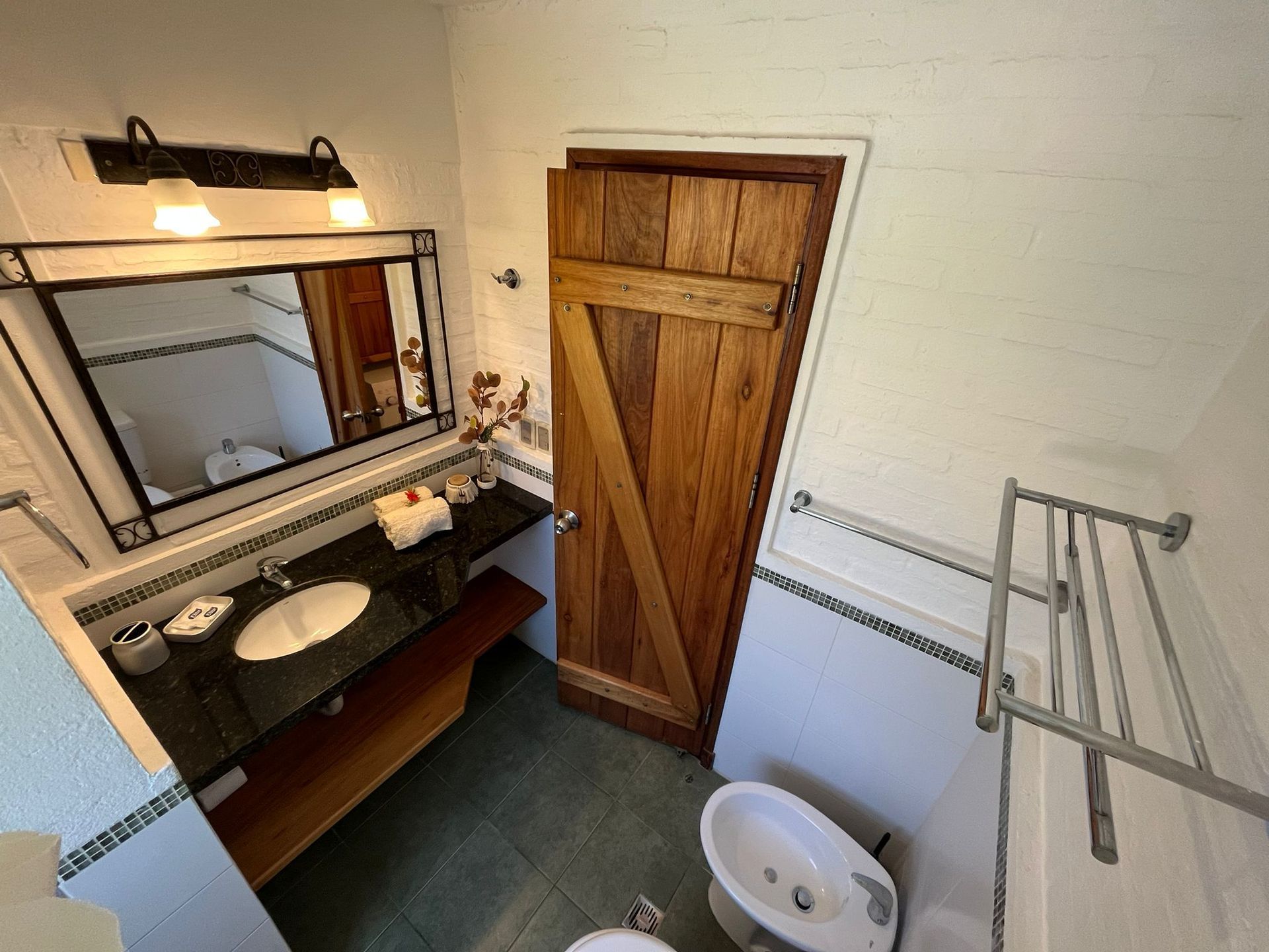 A bathroom with a sink , toilet , mirror and wooden door.