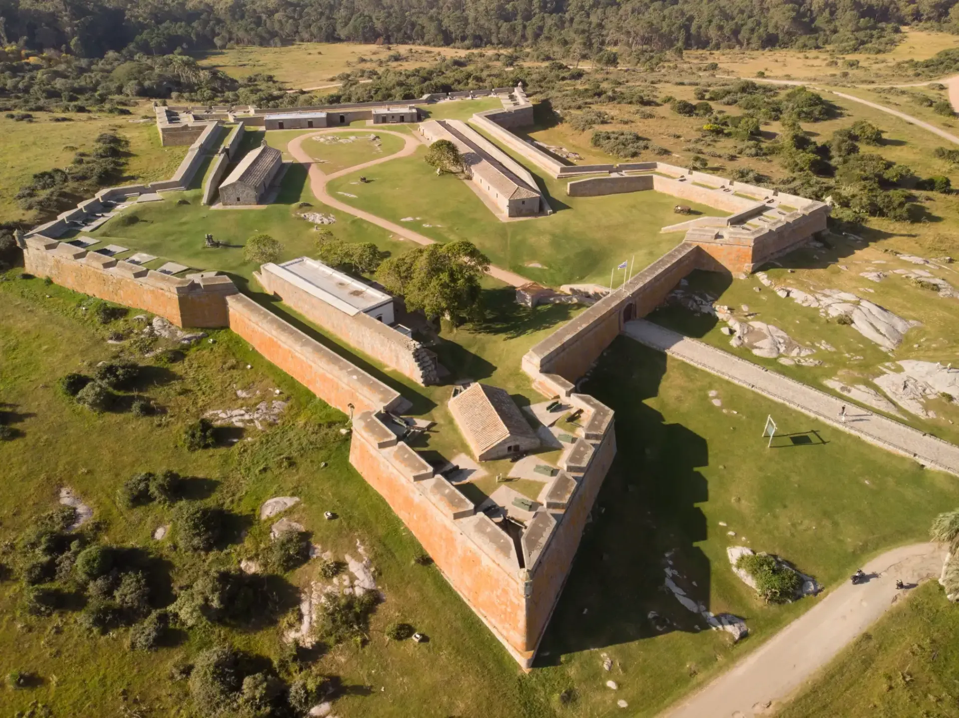 An aerial view of a large brick fort surrounded by grass and trees.
