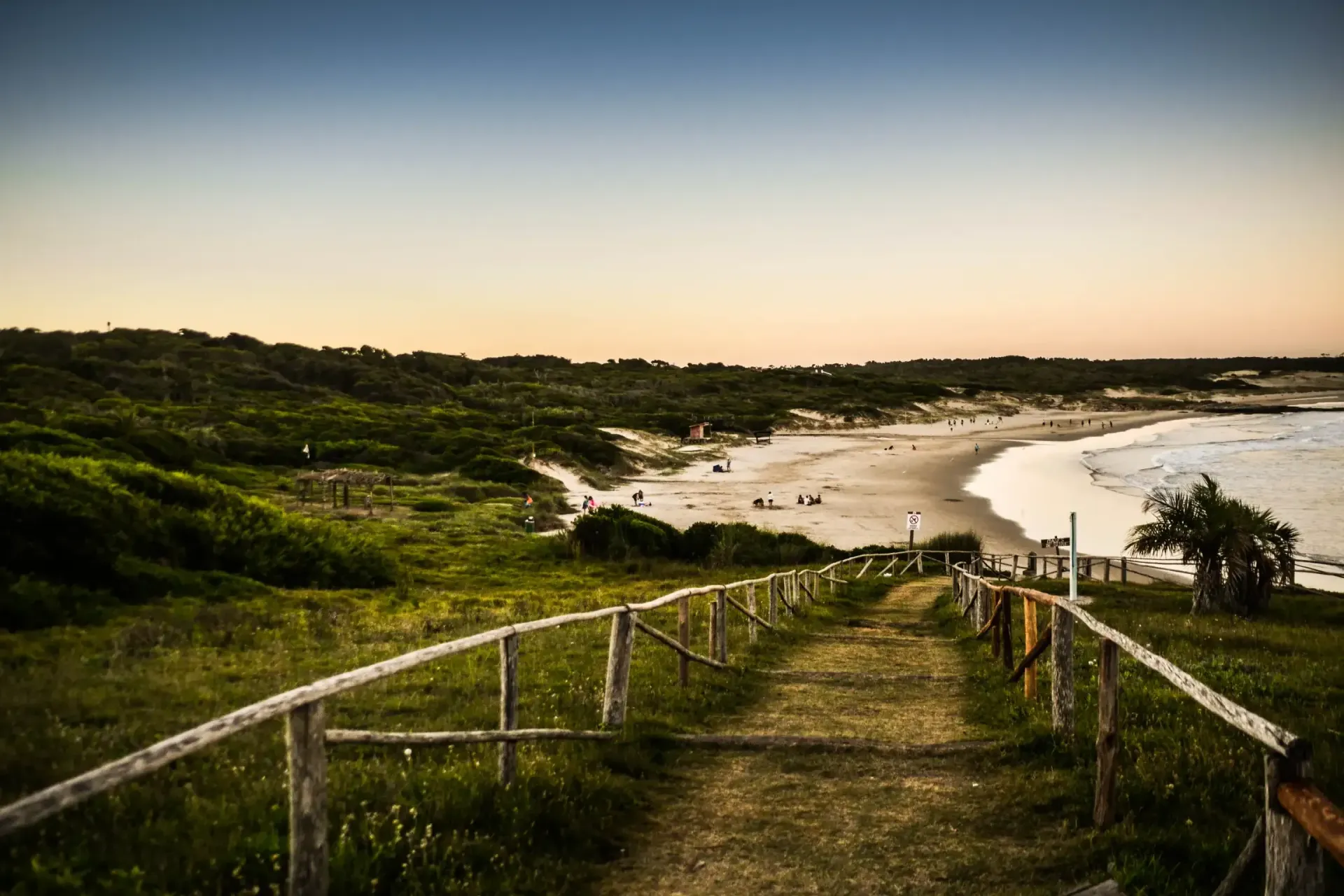 A path leading to a beach with a wooden fence.