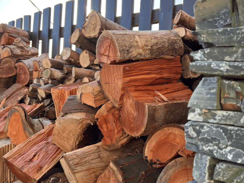 A pile of logs stacked on top of each other in front of a fence.