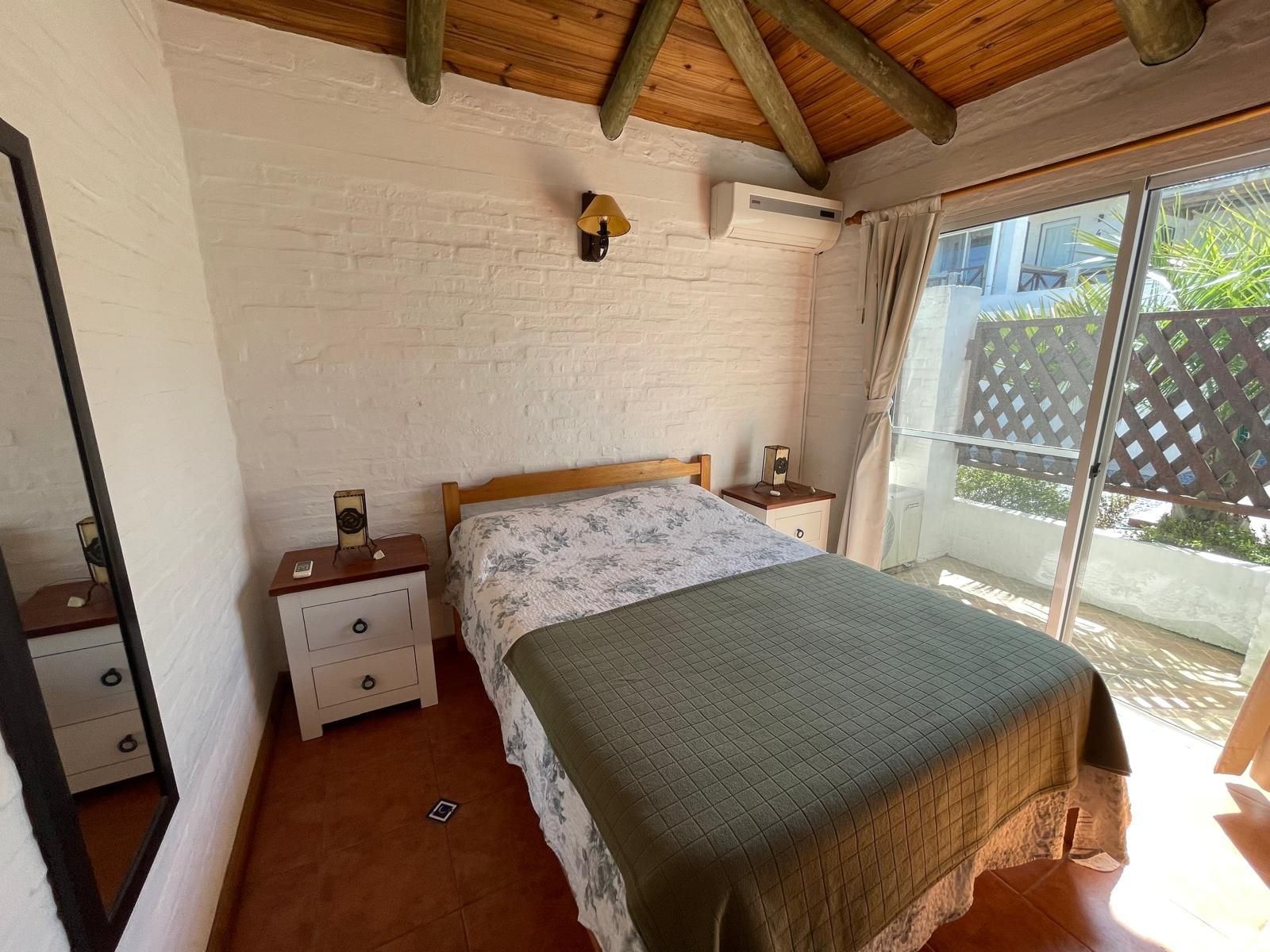A bedroom with a bed , nightstands , a mirror and a sliding glass door.