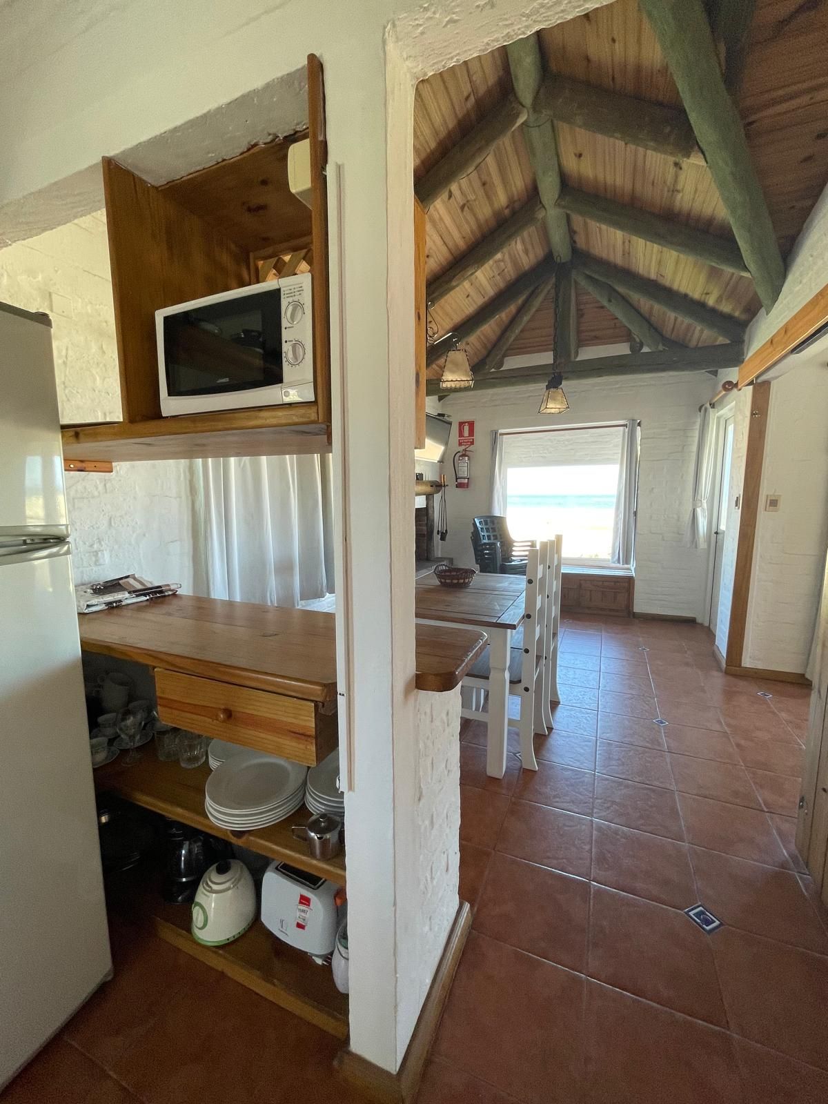 A kitchen with a microwave on top of a wooden shelf.