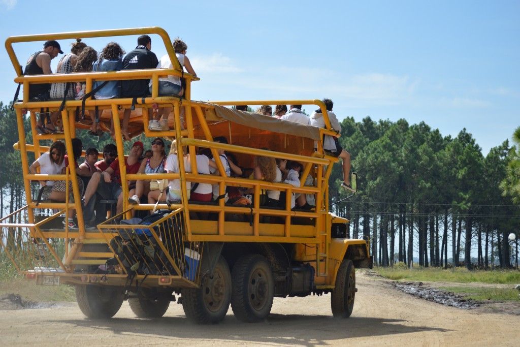 A group of people are riding on the back of a yellow truck.