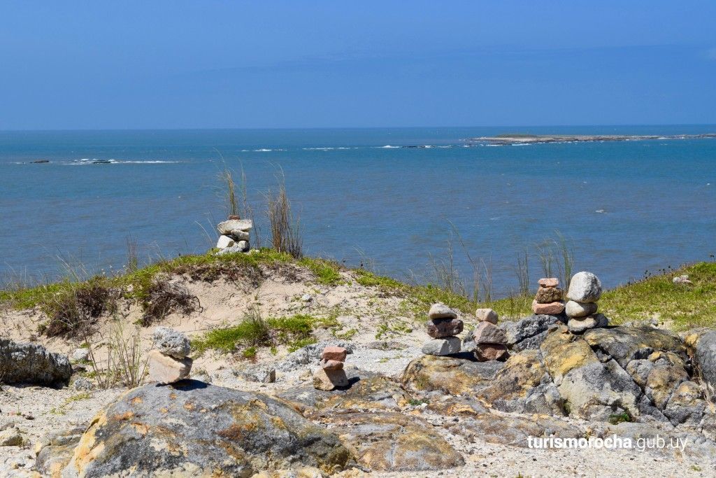 A group of rocks stacked on top of each other on a beach near the ocean.
