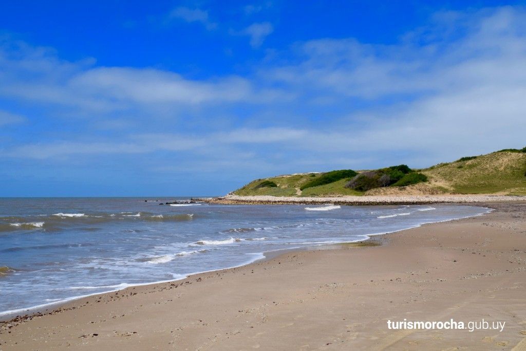 A beach with a blue sky and white clouds in the background