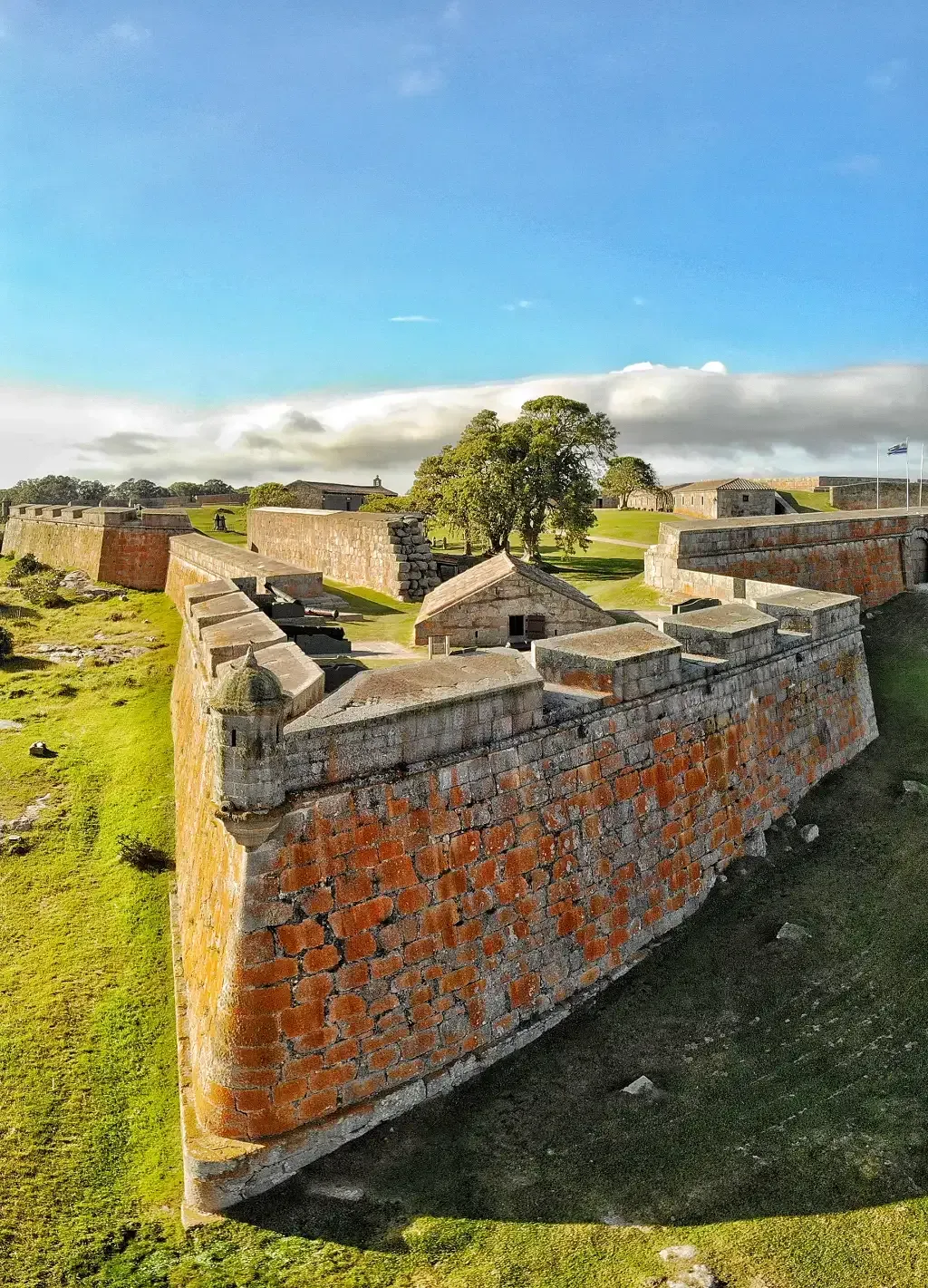There is a large brick wall in the middle of a field.