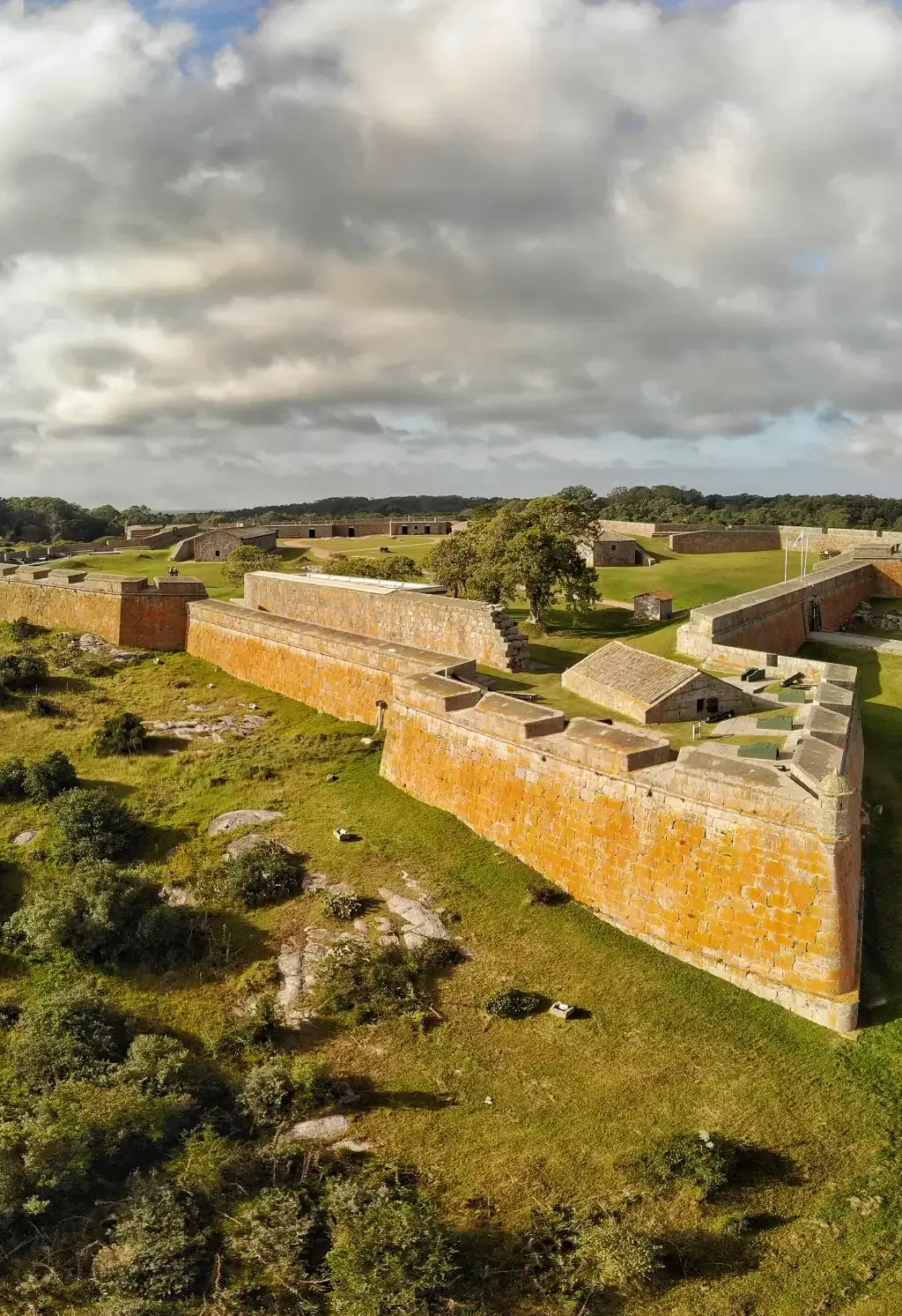 An aerial view of a large brick wall surrounded by grass and trees.