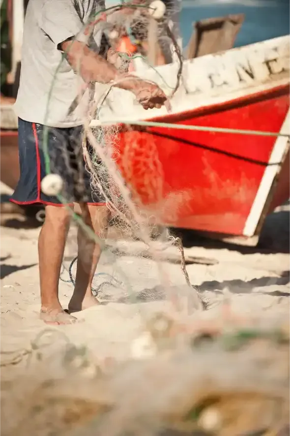 A man is holding a fishing net in front of a red boat.