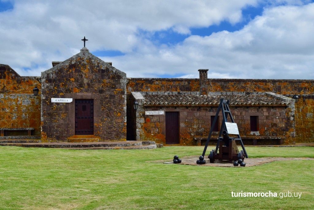 A large stone building with a cannon in front of it.