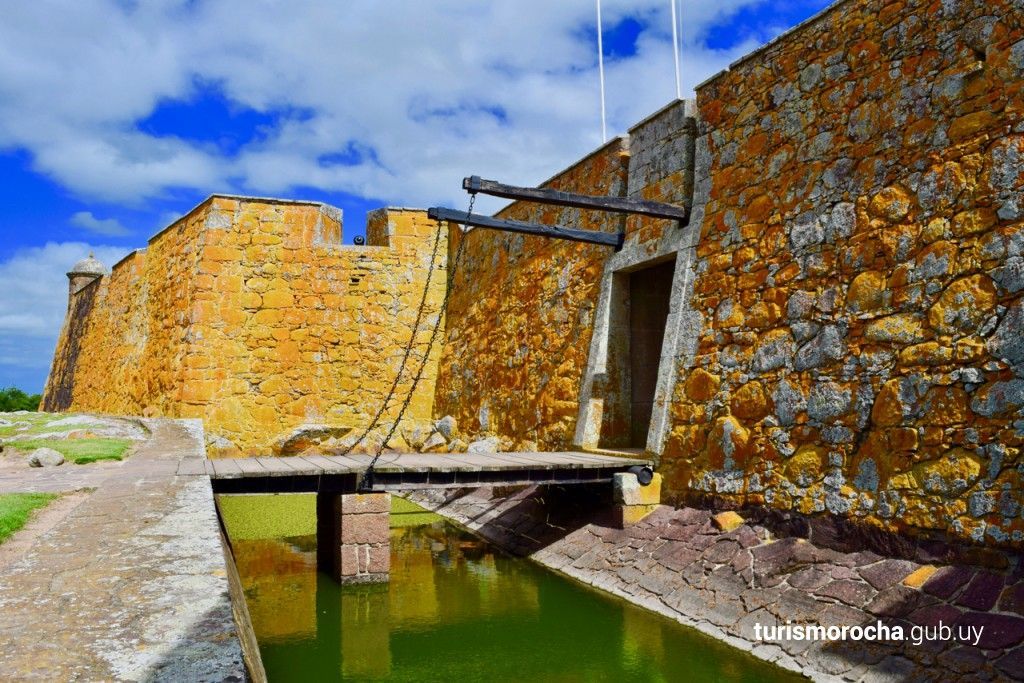 A stone wall with a bridge over a body of water.