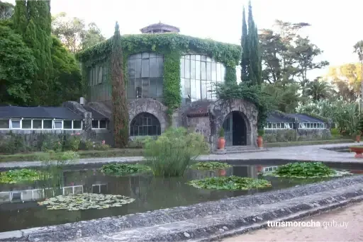 A large building with a pond in front of it surrounded by trees.
