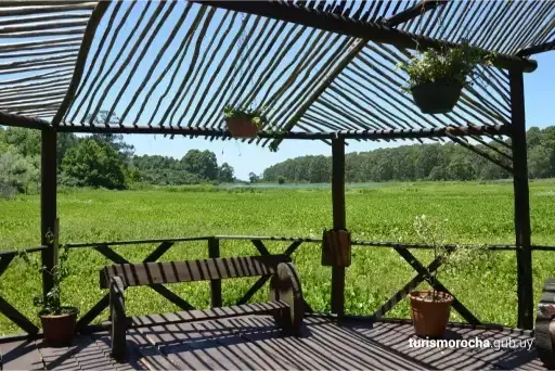 A wooden gazebo with a view of a green field